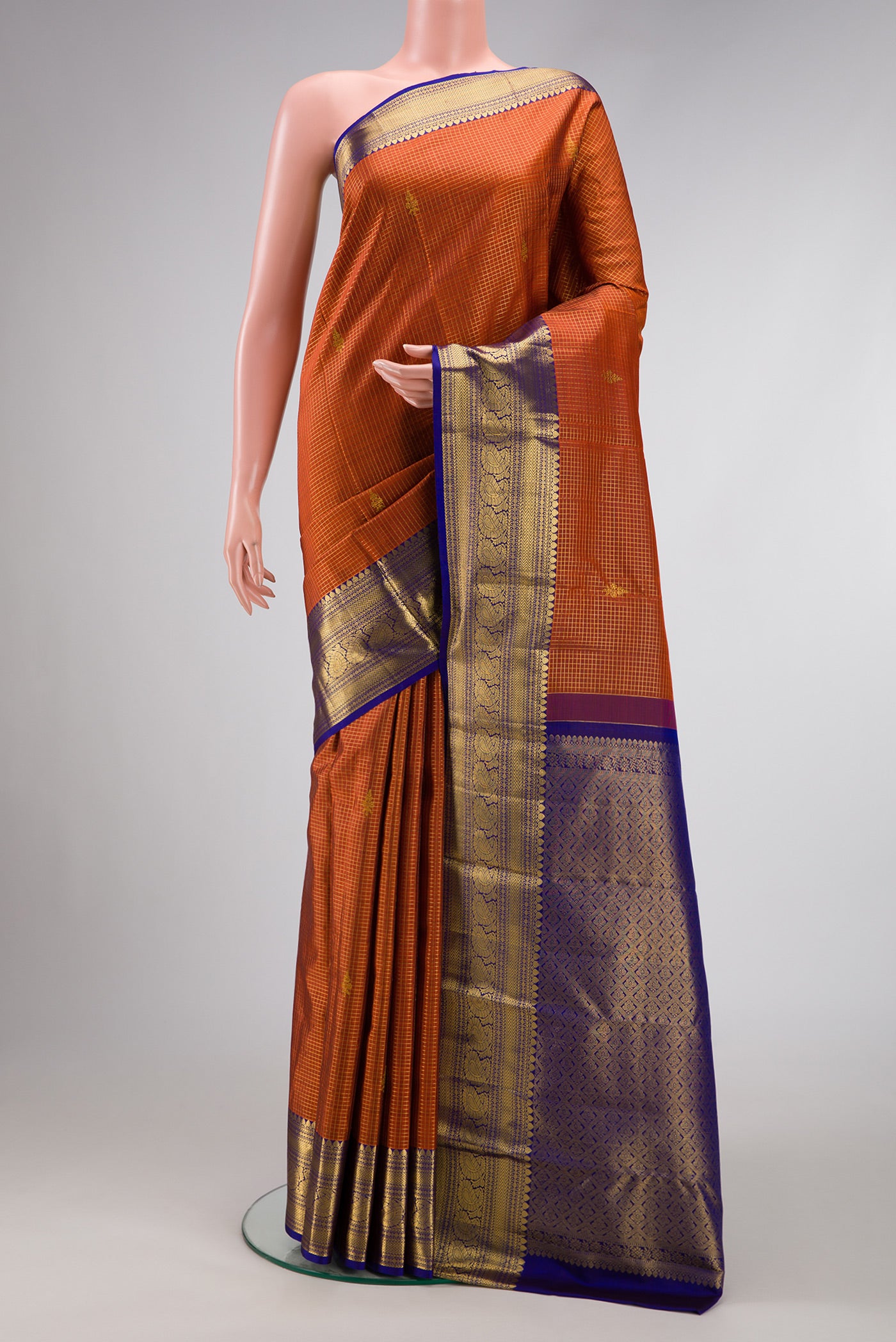 Orange Dual Tone Kanchipuram Silk Saree with Checked design on the body and Zari Border.  displayed on a mannequin