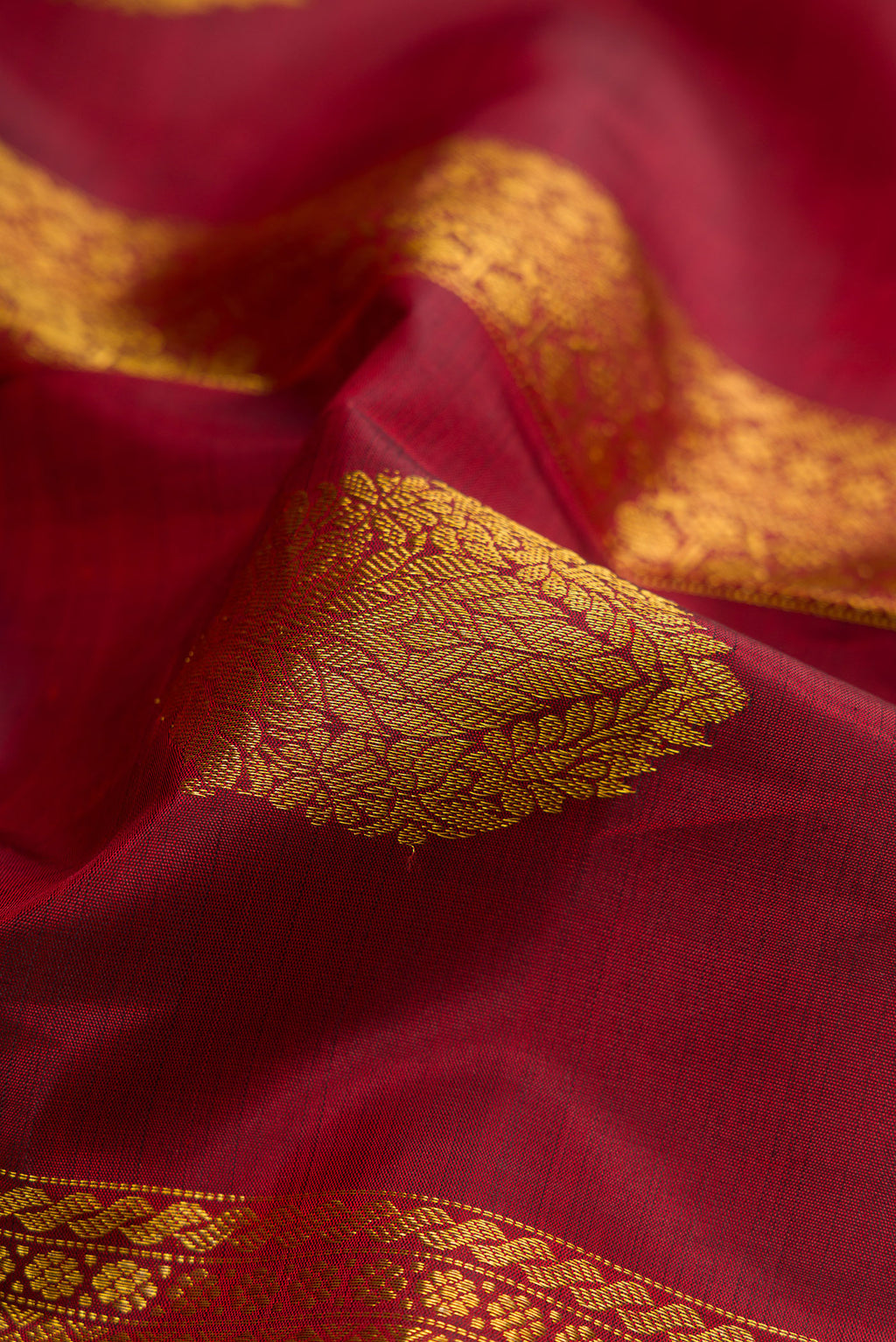 Close up of Maroon Kanchipuram Silk Saree with Stripes on the body and Zari Border.  displaying folds