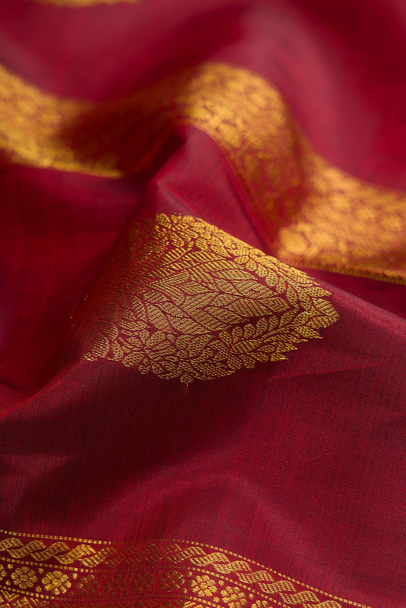Close up of Maroon Kanchipuram Silk Saree with Stripes on the body and Zari Border.  displaying folds