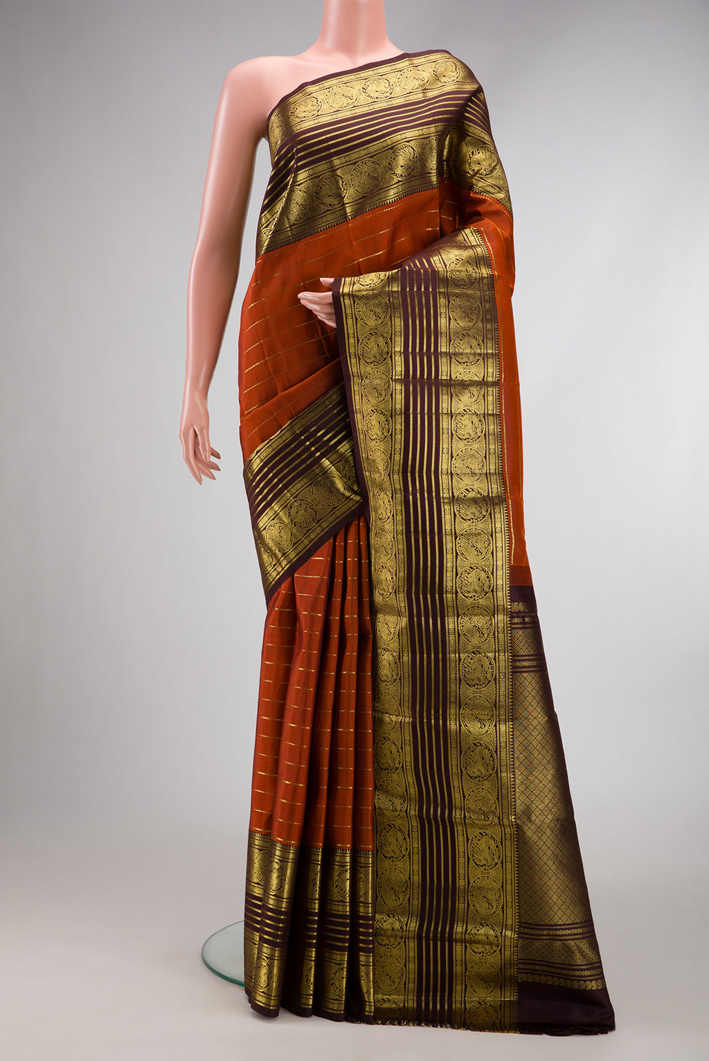 Brick Orange Dual Tone Kanchipuram Silk Saree with Stripes on the body and Zari Border.  displayed on a mannequin