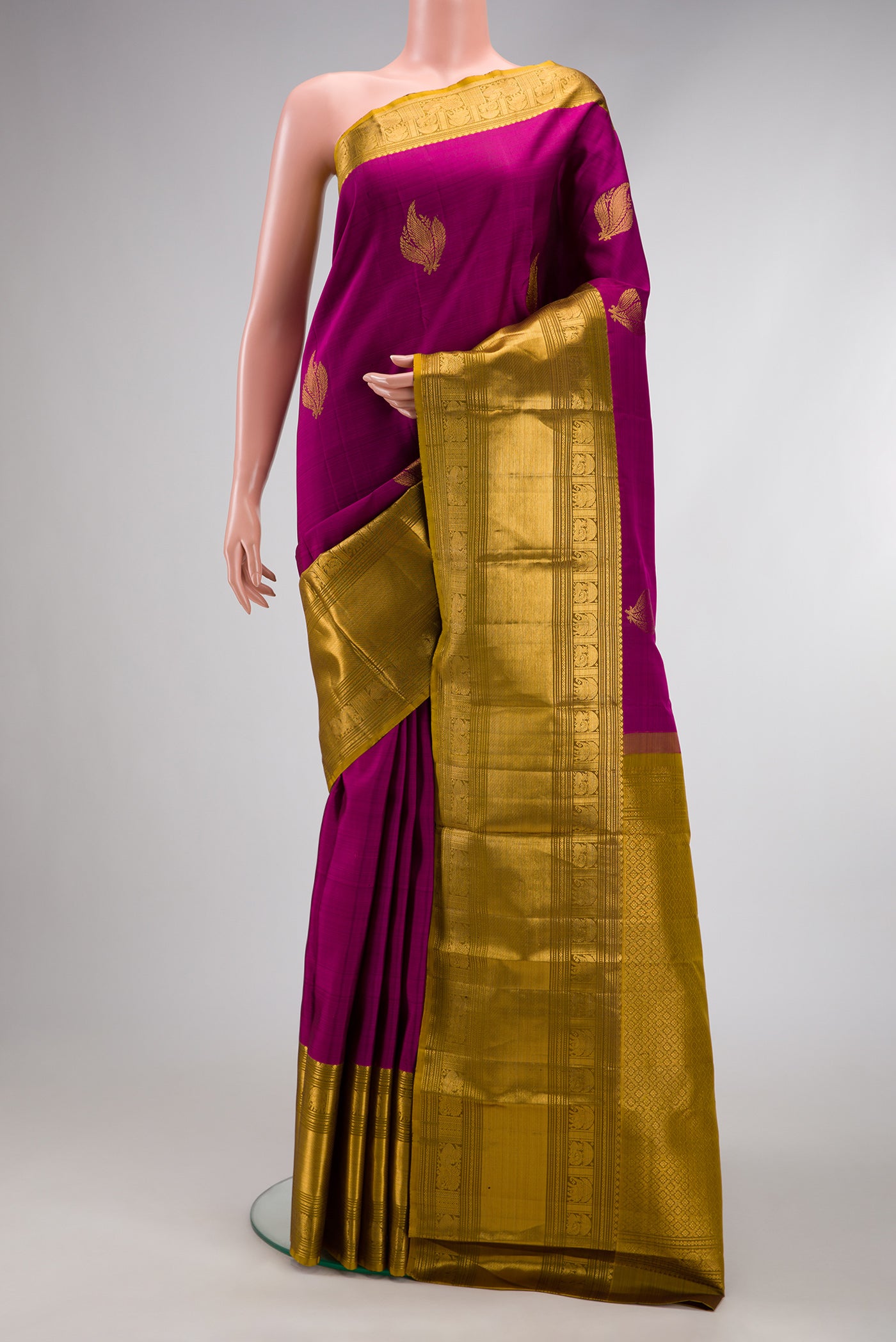 Magenta Kanchipuram Silk Saree with Zari Butta on the body and Zari Border.  displayed on a mannequin
