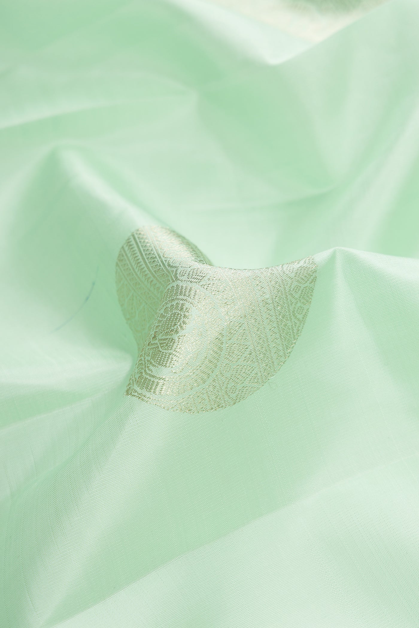 Close up of Pista Green Dual Tone Kanchipuram Silk Saree with Zari Butta on the body and Zari Border.  displaying folds