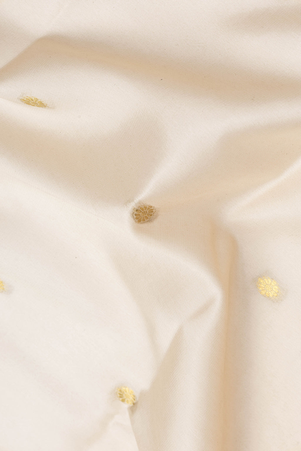 Close up of Off White Dual Tone Mysore Silk Saree with Zari Butta on the body and Zari Border.  displaying folds