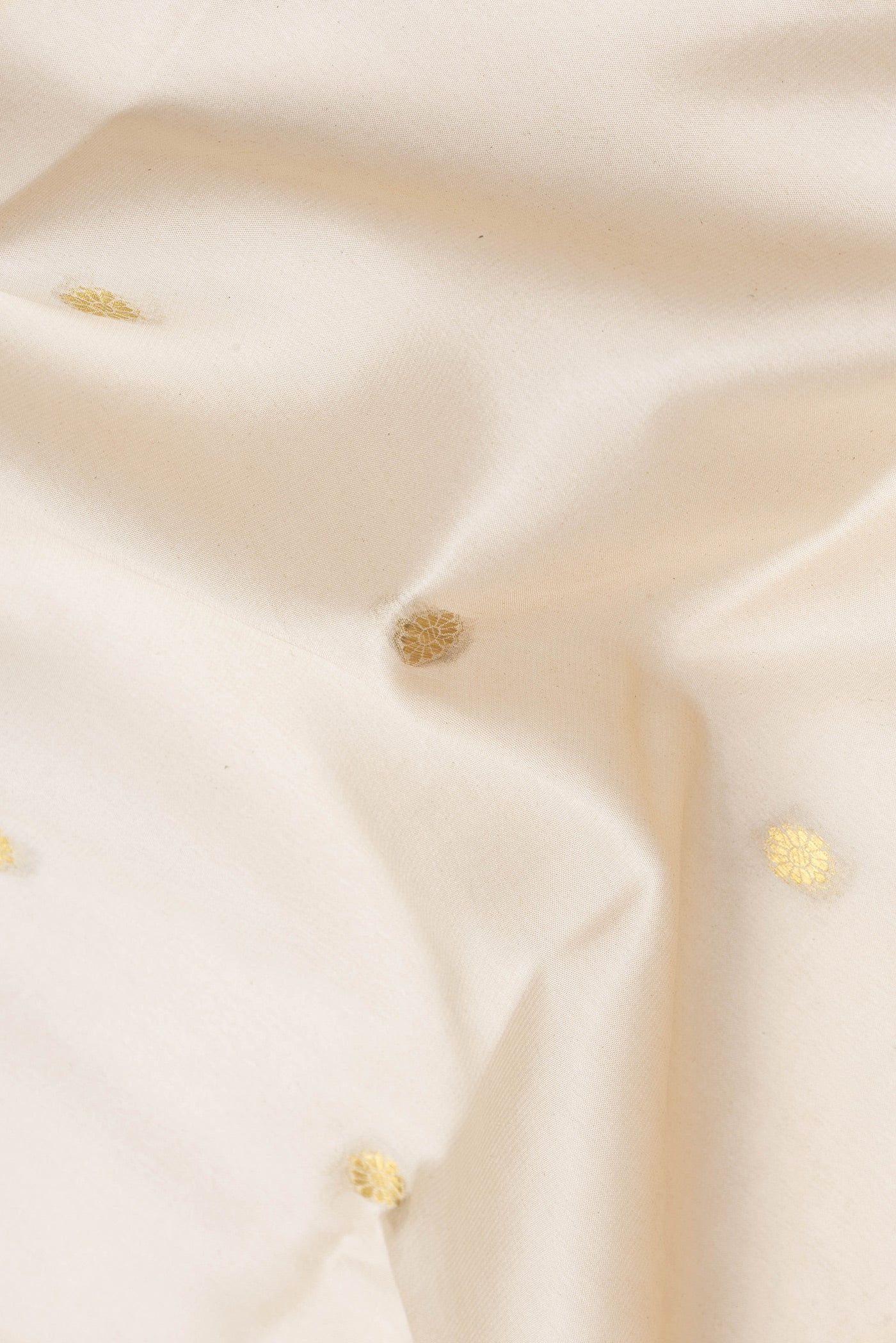 Close up of Off White Dual Tone Mysore Silk Saree with Zari Butta on the body and Zari Border.  displaying folds