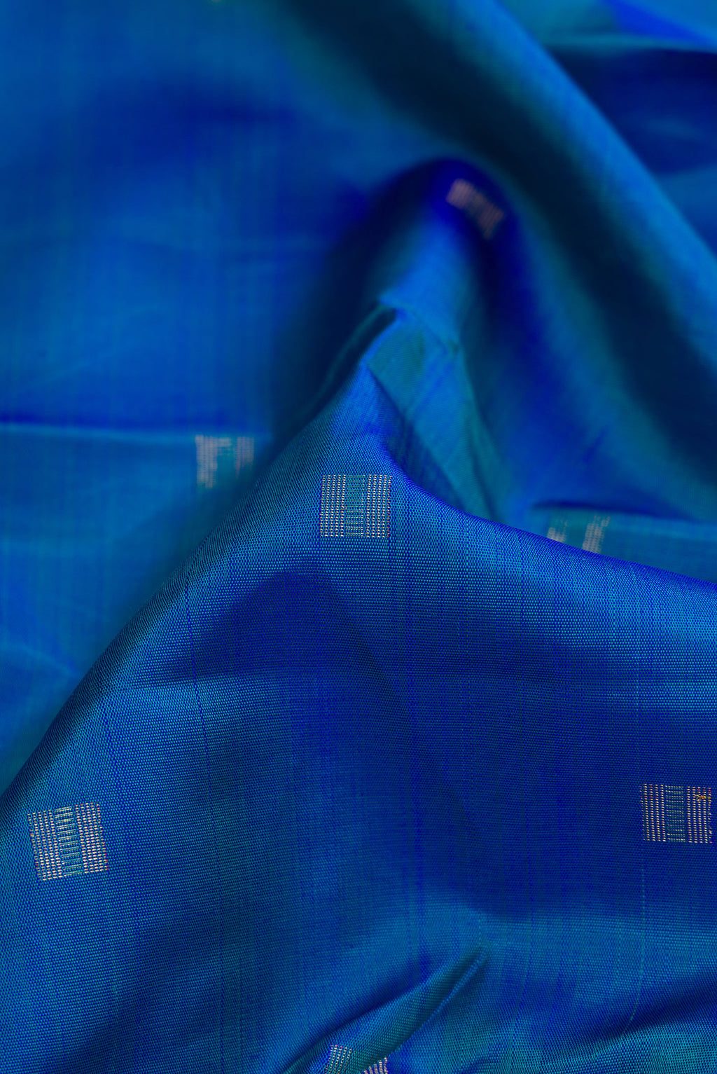 Close up of Pure Silk Pure Zari Peacock Blue Dual Tone Kanchipuram Saree with Zari Butta on the body and Zari Border.  displaying folds