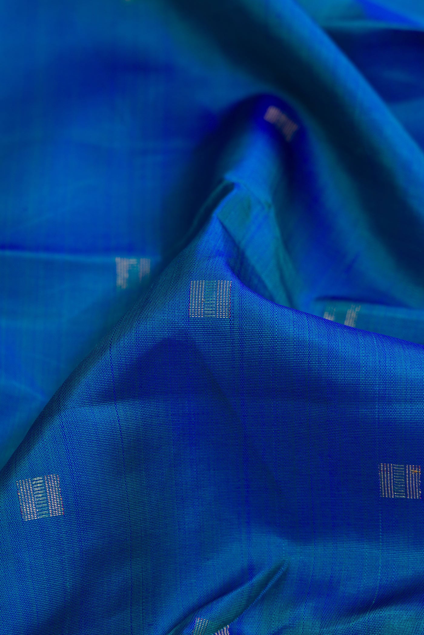 Close up of Pure Silk Pure Zari Peacock Blue Dual Tone Kanchipuram Saree with Zari Butta on the body and Zari Border.  displaying folds