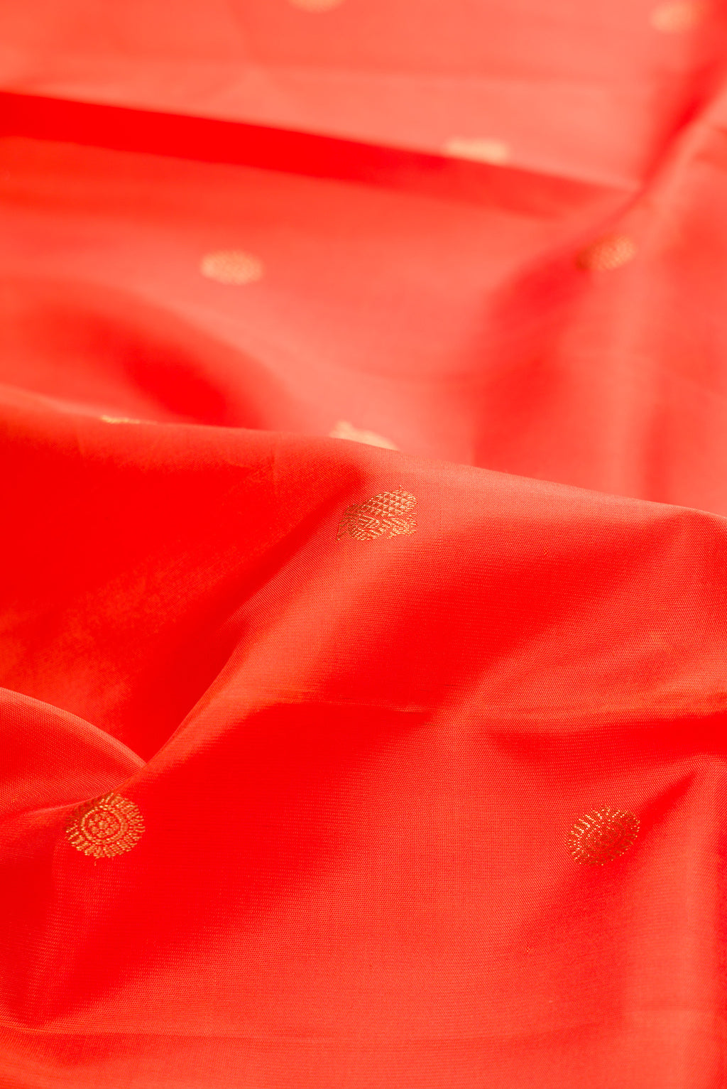 Close up of Pure Silk Pure Zari Orange Kanchipuram Saree with Zari Butta on the body and Fancy Border.  displaying folds