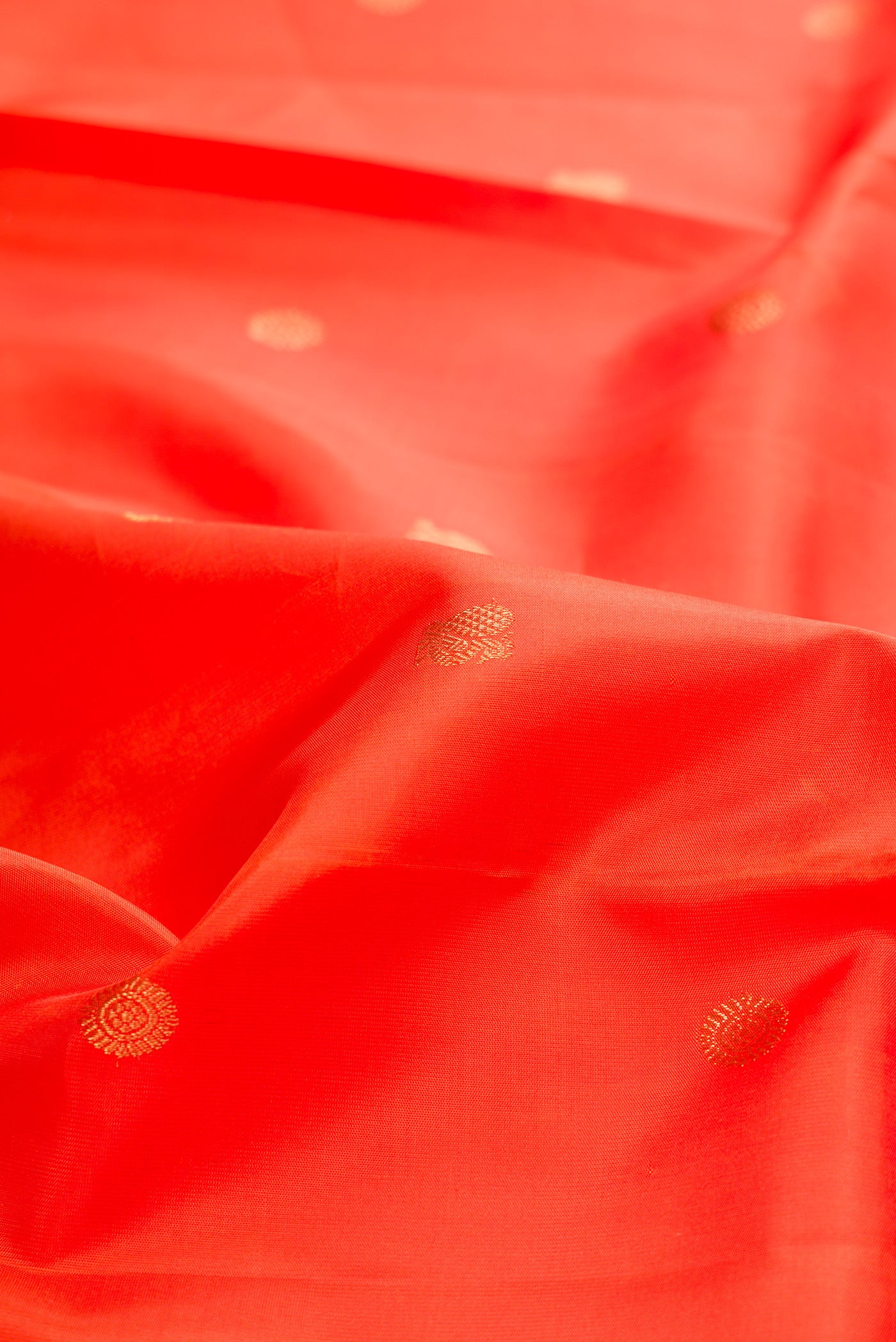 Close up of Pure Silk Pure Zari Orange Kanchipuram Saree with Zari Butta on the body and Fancy Border.  displaying folds
