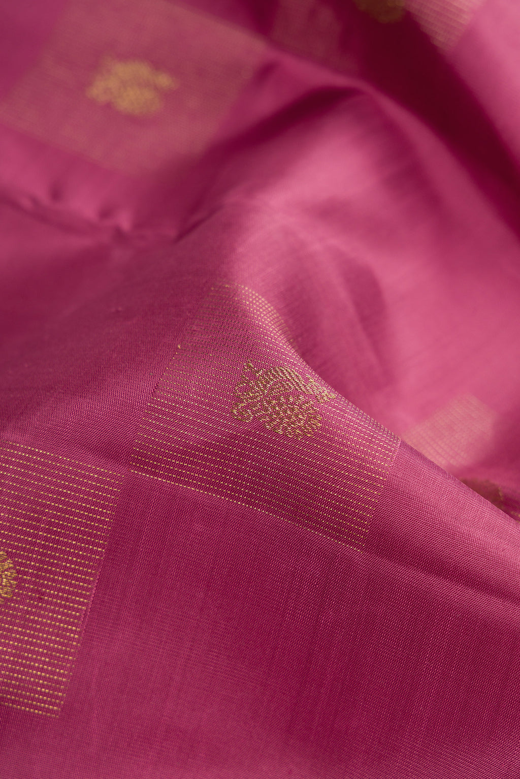 Close up of Pure Silk Pure Zari Rose Gold Dual Tone Kanjivaram Saree with Zari Butta on the body and Without Border.  displaying folds