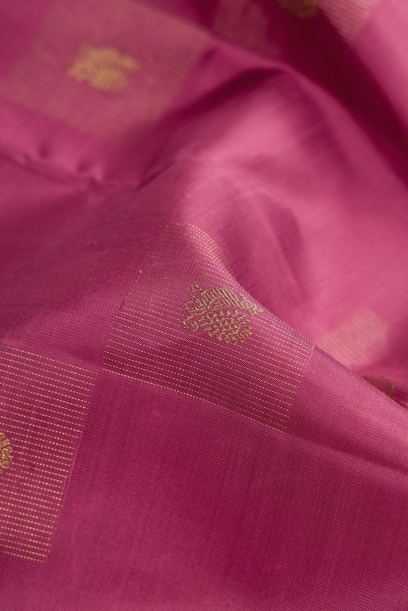 Close up of Pure Silk Pure Zari Rose Gold Dual Tone Kanjivaram Saree with Zari Butta on the body and Without Border.  displaying folds