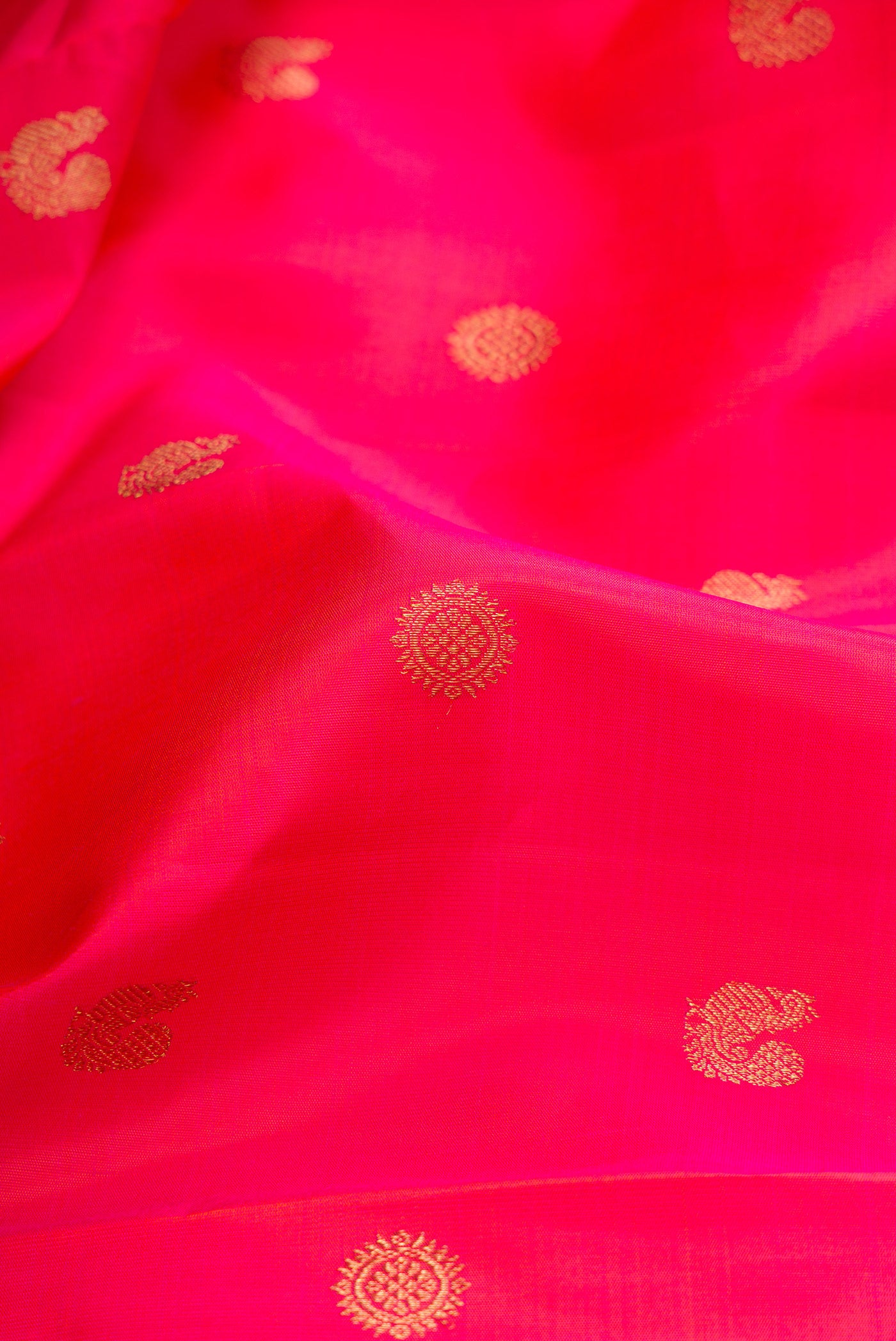 Close up of Pure Silk Pure Zari Coral Dual Tone Kanchipuram Saree with Zari Butta on the body and Fancy Border.  displaying folds