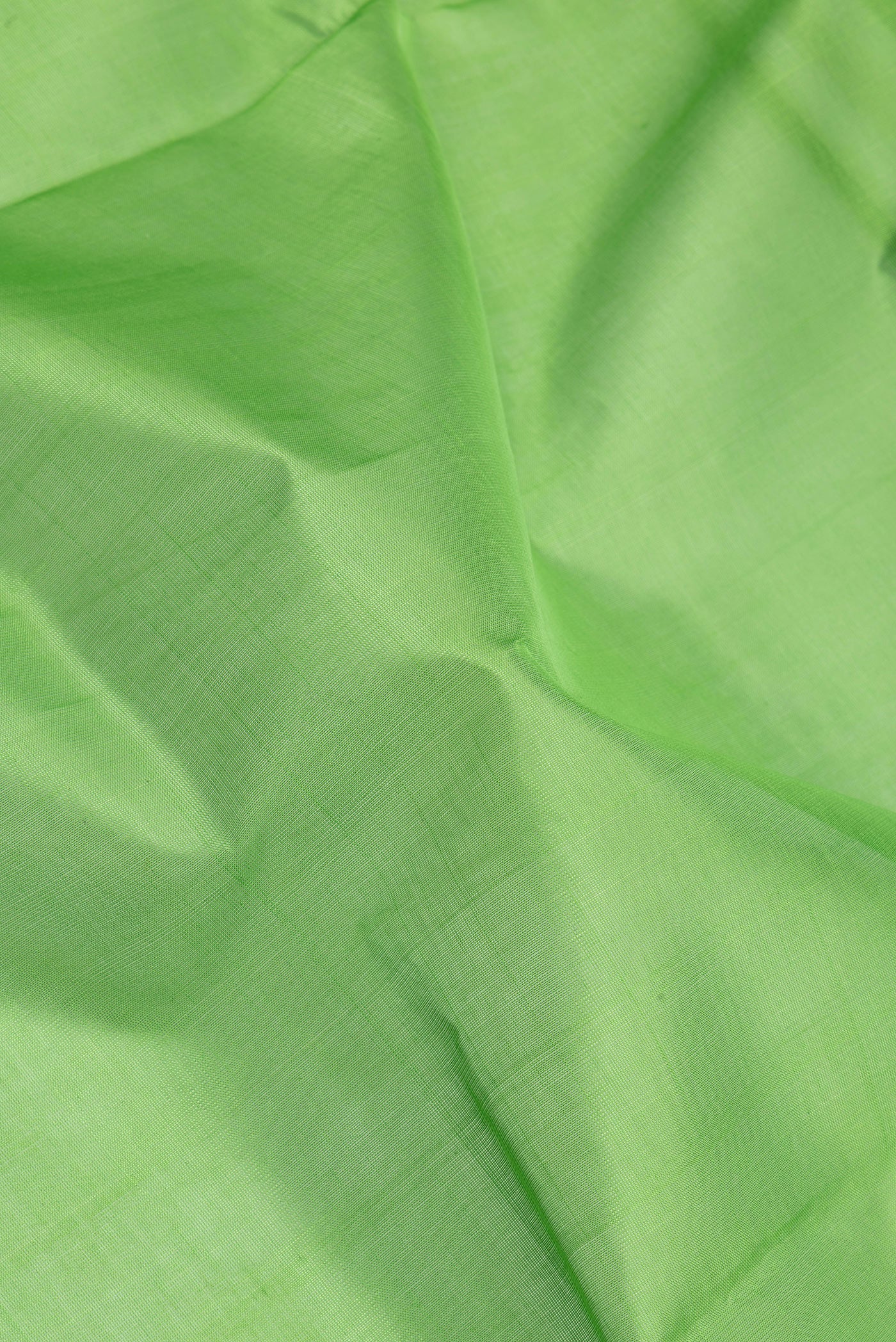 Close up of Green Silk Cotton Saree with Plain Body and Zari Border.  displaying folds