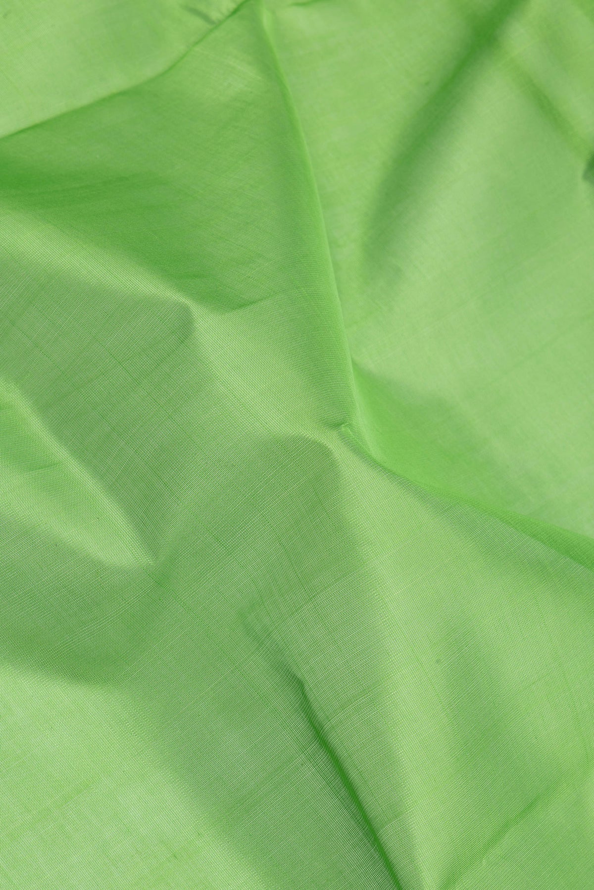 Close up of Green Silk Cotton Saree with Plain Body and Zari Border.  displaying folds
