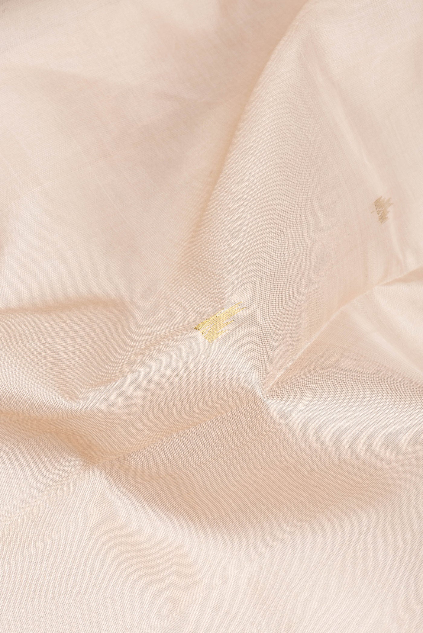 Close up of Beige Silk Cotton Saree with Zari Butta on the body and Zari Border.  displaying folds