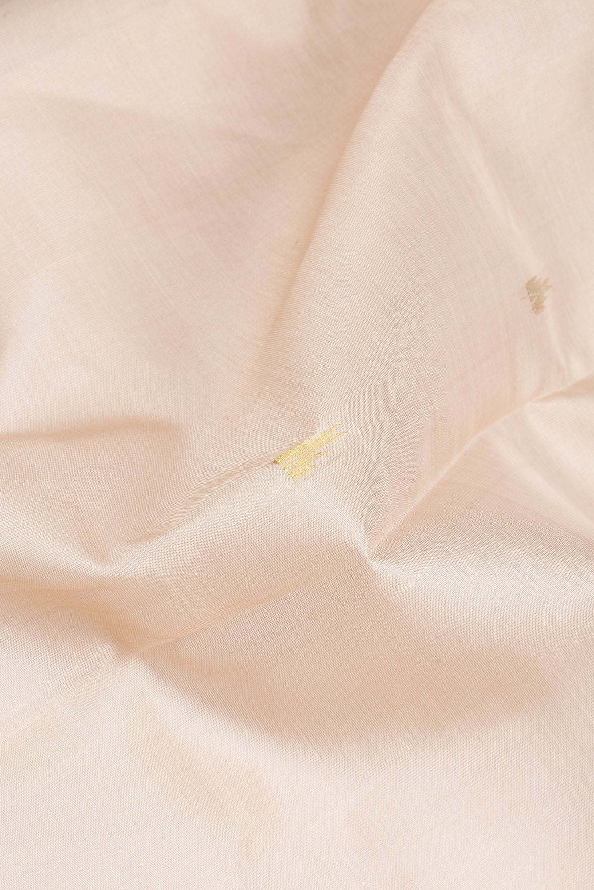 Close up of Beige Silk Cotton Saree with Zari Butta on the body and Zari Border.  displaying folds