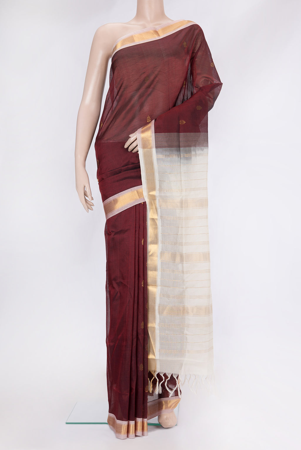Maroon Silk Cotton Saree with Zari Butta on the body and Zari Border.  displayed on a mannequin
