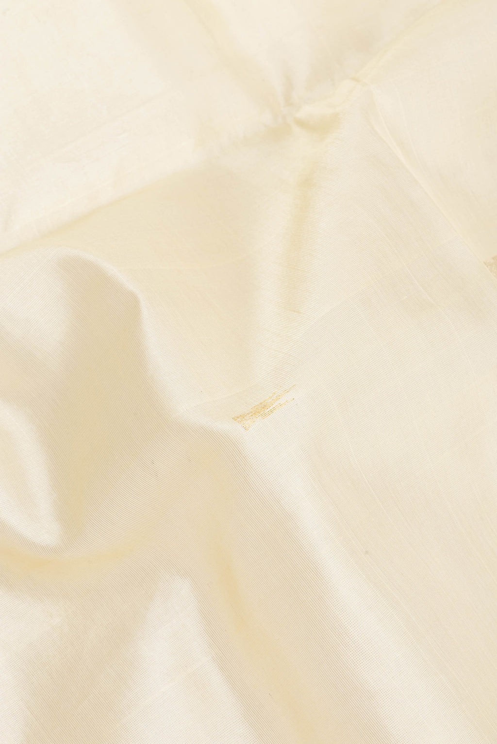 Close up of Cream Silk Cotton Saree with Zari Butta on the body and Zari Border.  displaying folds