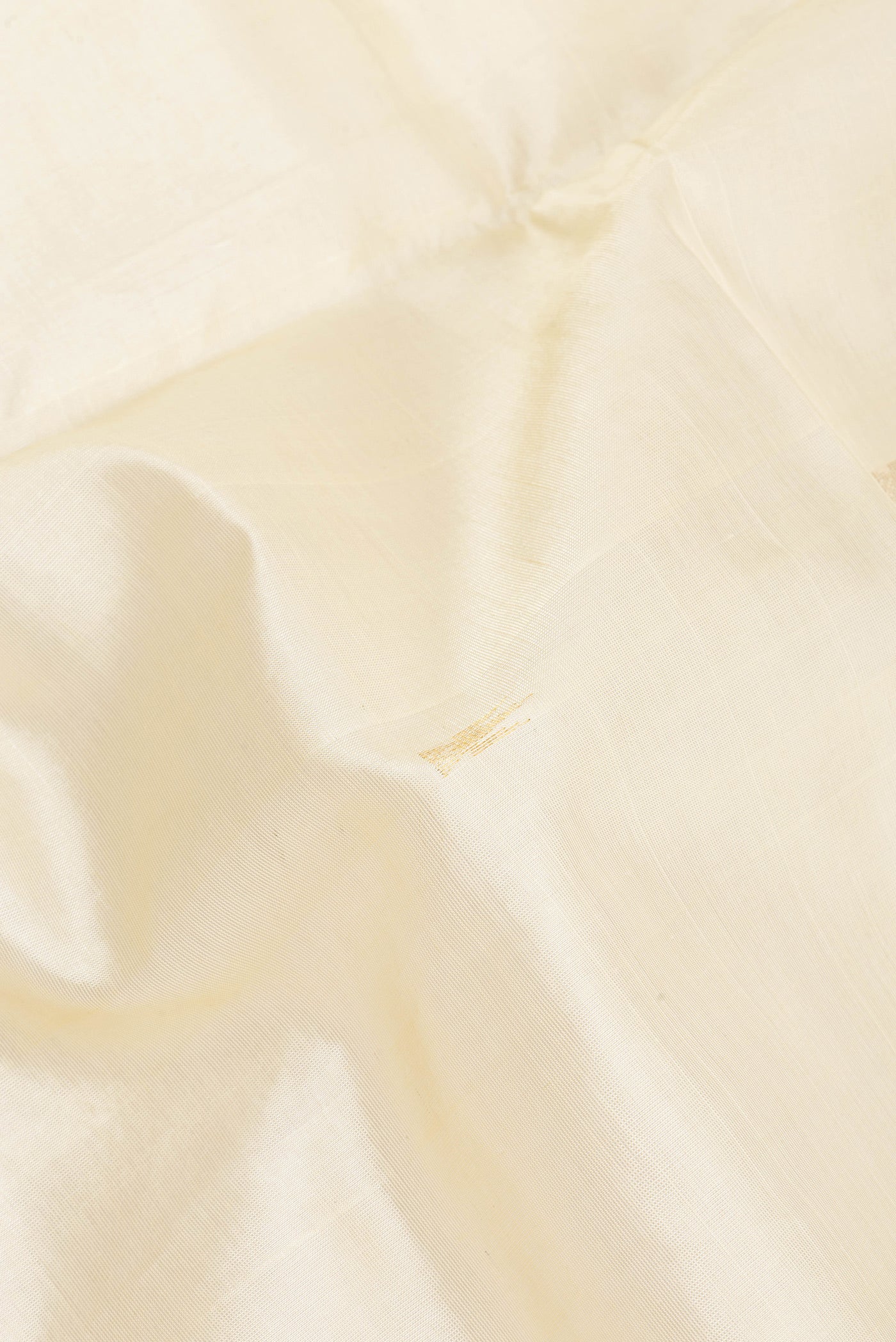 Close up of Cream Silk Cotton Saree with Zari Butta on the body and Zari Border.  displaying folds