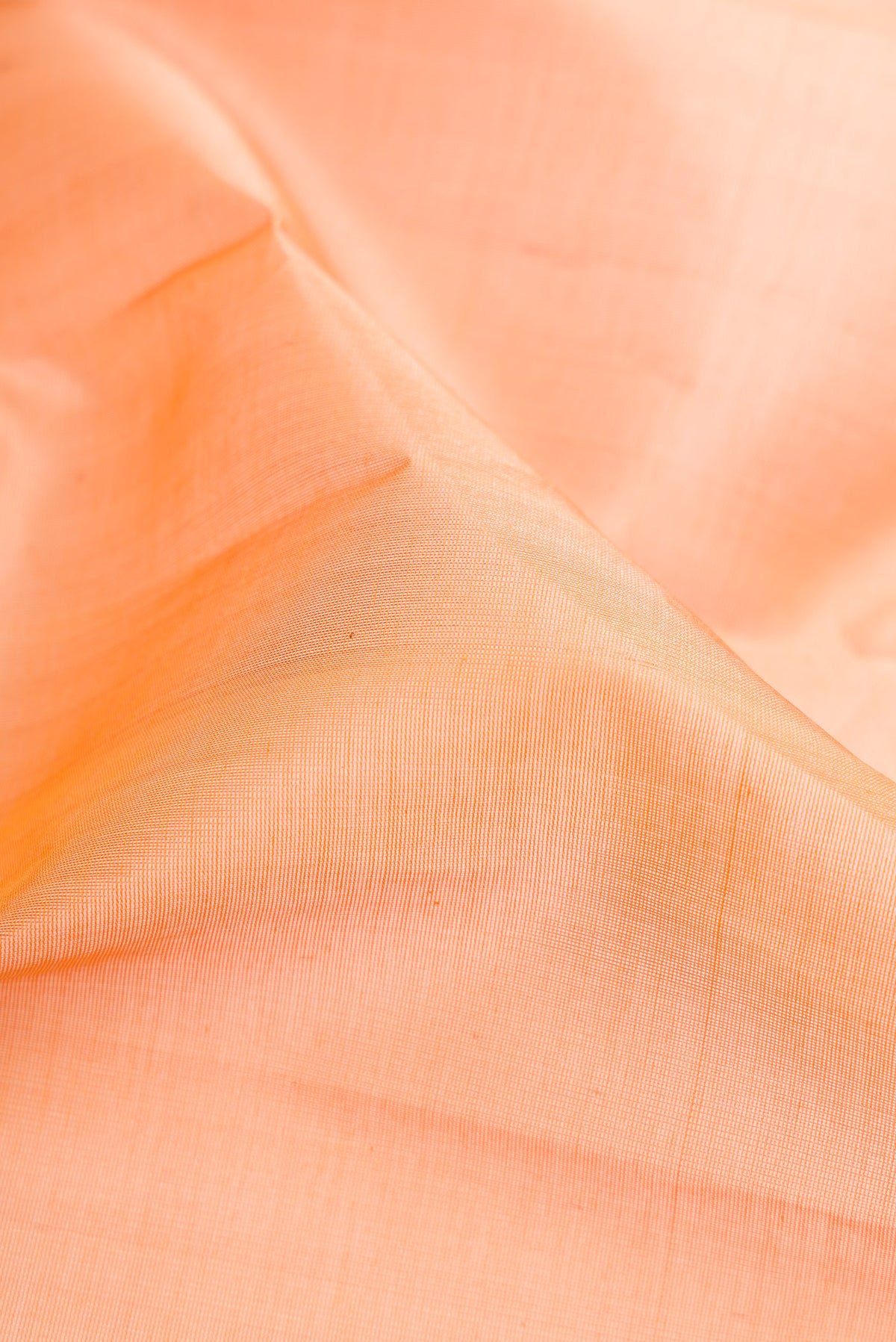 Close up of Peach Silk Cotton Saree with Plain Body and Zari Border.  displaying folds