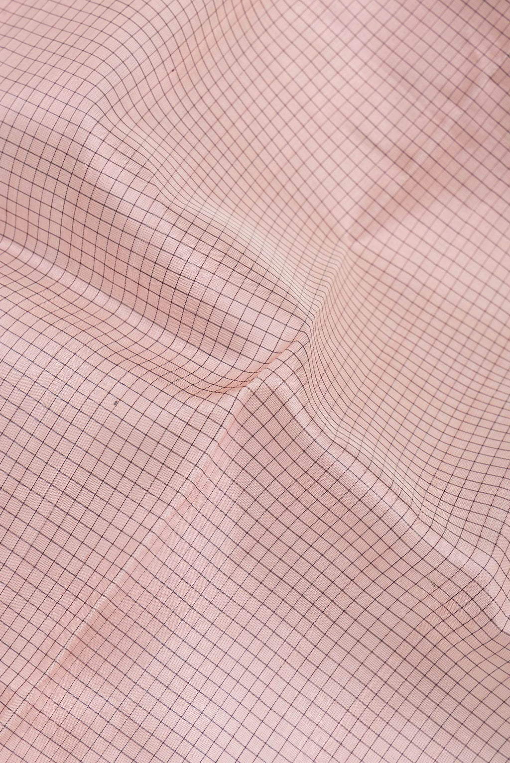 Close up of Rose Gold Silk Cotton Saree with Checked design on the body and Zari Border.  displaying folds