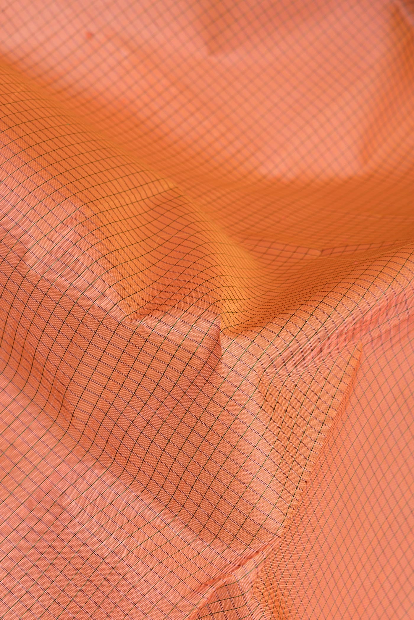 Close up of Orange Silk Cotton Saree with Checked design on the body and Zari Border.  displaying folds
