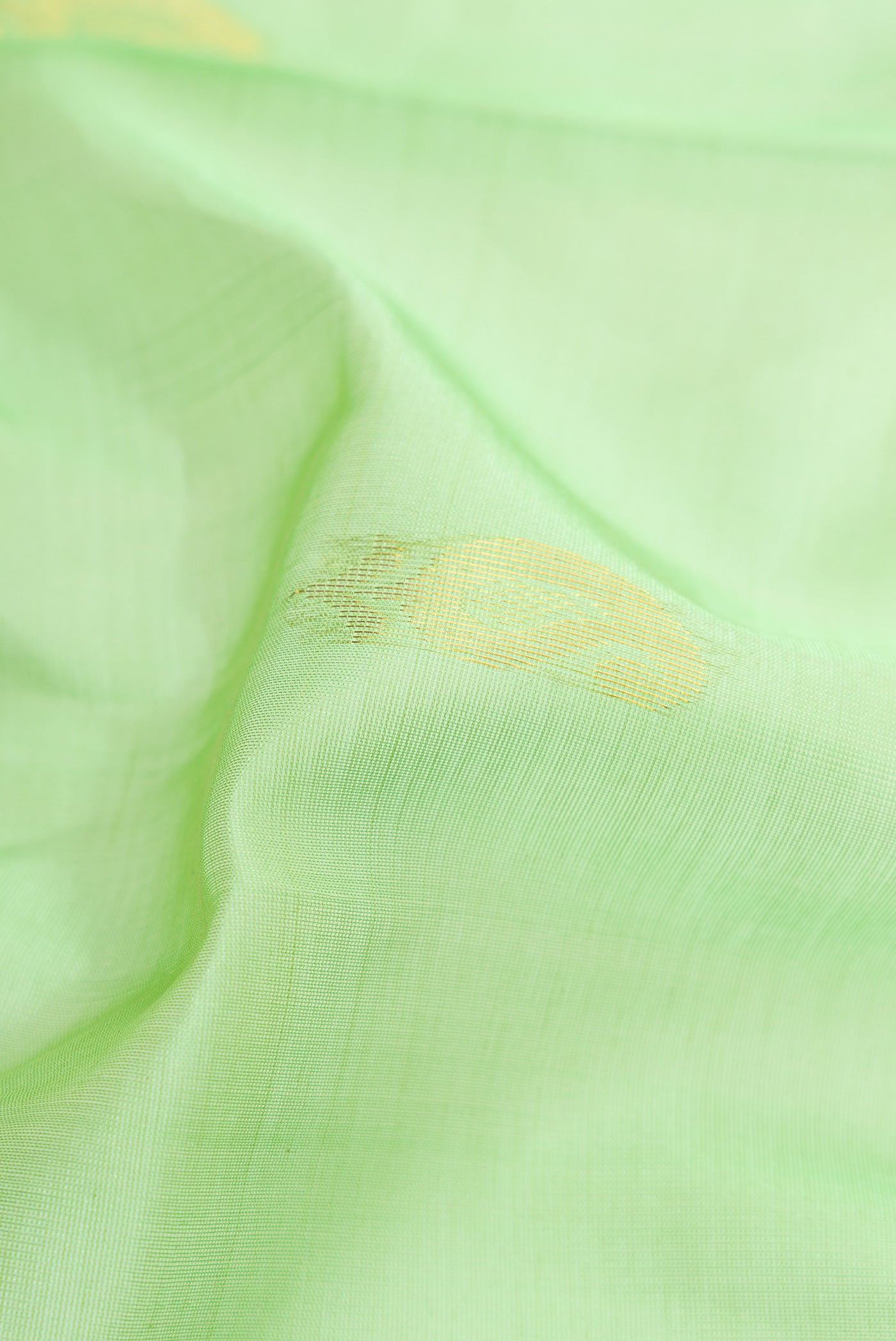 Close up of Pista Green Dual Tone Silk Cotton Saree with Zari Butta on the body and Zari Border.  displaying folds