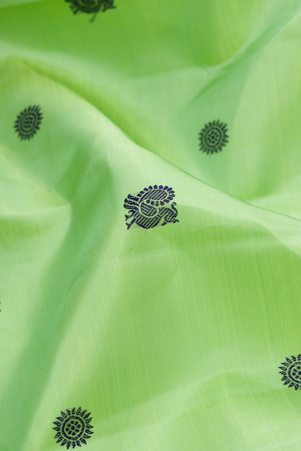Close up of Pure Silk Pure Zari Green Dual Tone Kanchipuram Saree with Thread Butta on the body and Zari And Thread Border.  displaying folds