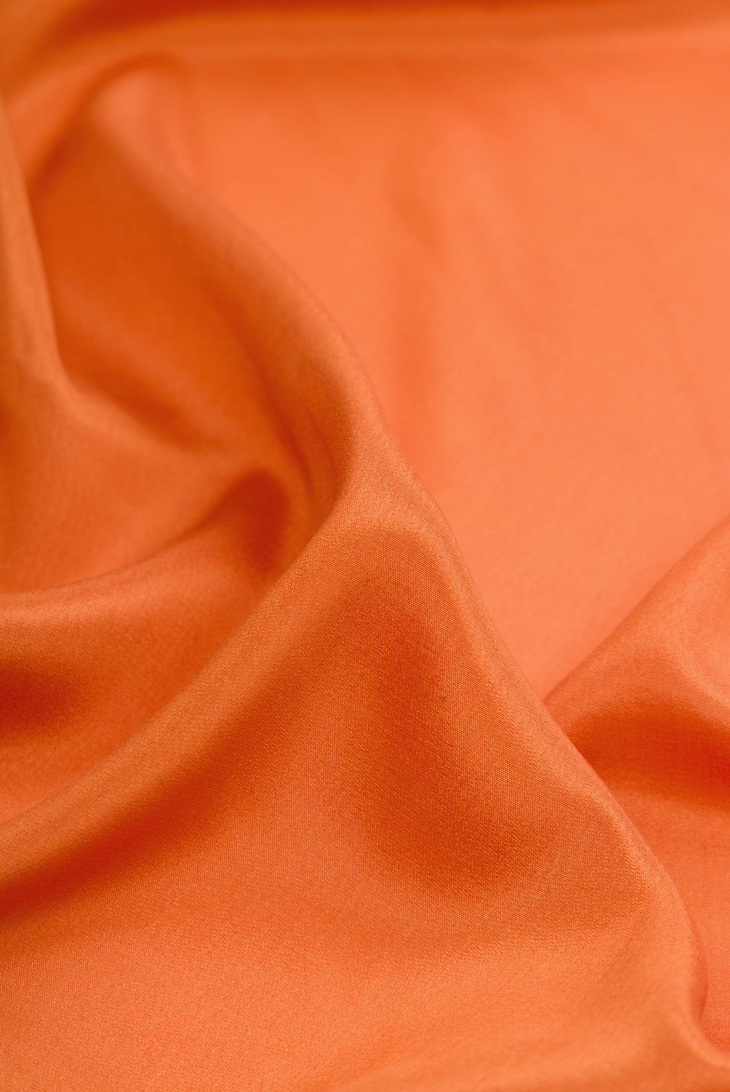 Close up of Orange Dual Tone Crepe Saree with Plain Body and Fancy Border.  displaying folds