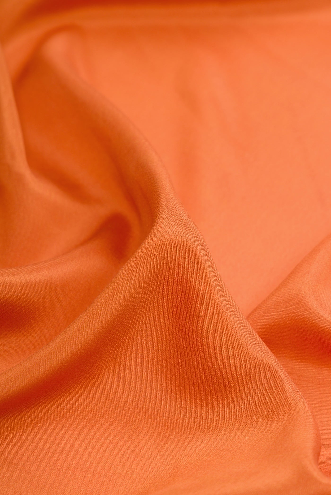 Close up of Orange Dual Tone Crepe Saree with Plain Body and Fancy Border.  displaying folds