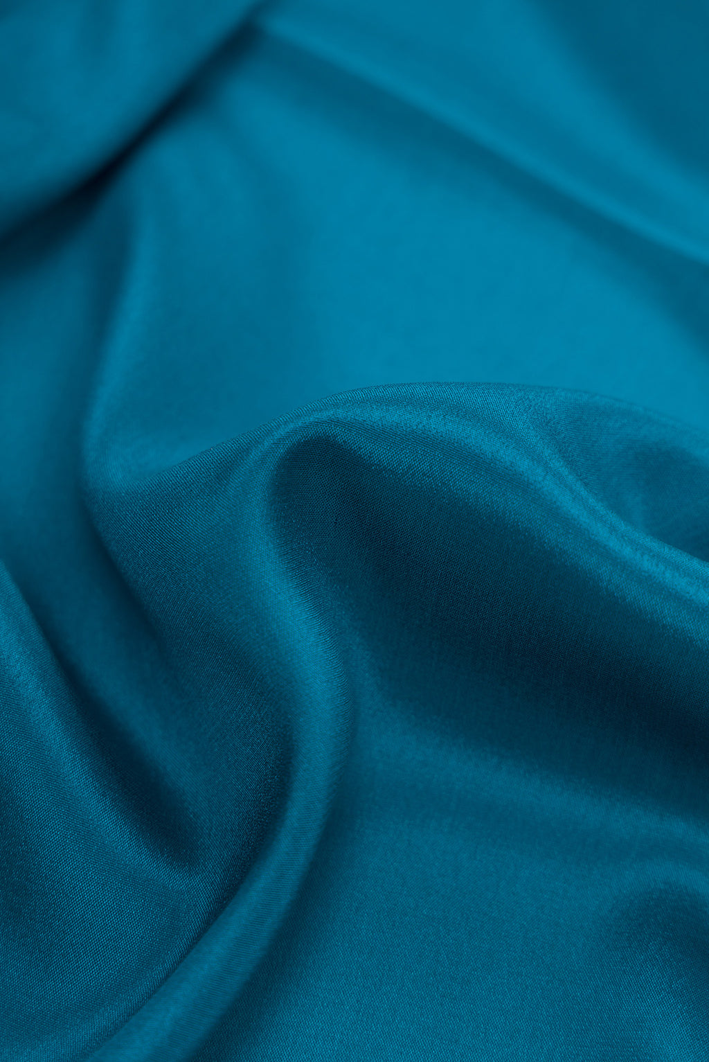 Close up of Peacock Blue Dual Tone Mysore Crepe Saree with Plain Body and Fancy Border.  displaying folds