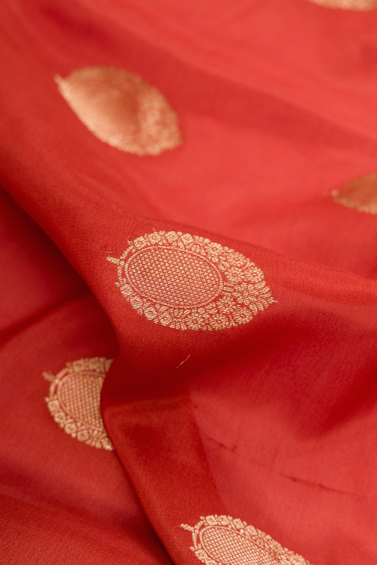 Close up of Orange Dual Tone Georgette Saree with Zari Butta on the body and Zari Border.  displaying folds