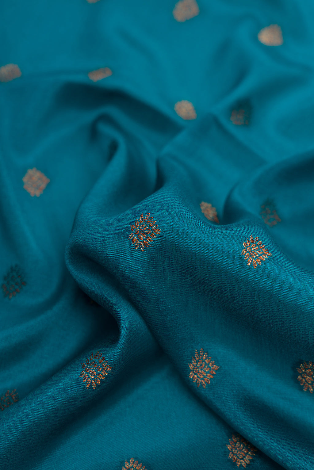 Close up of Peacock Blue Dual Tone Mysore Crepe Saree with Zari Butta on the body and Fancy Border.  displaying folds