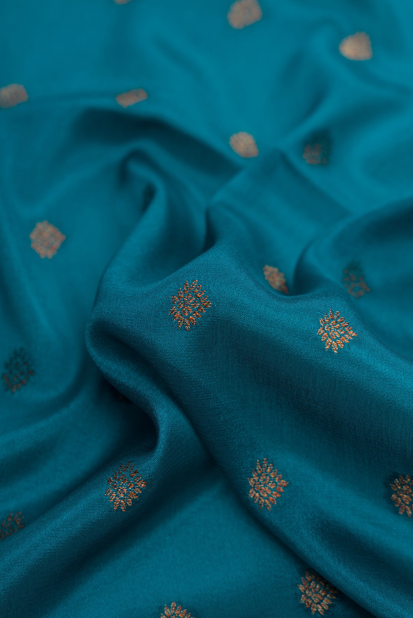 Close up of Peacock Blue Dual Tone Mysore Crepe Saree with Zari Butta on the body and Fancy Border.  displaying folds