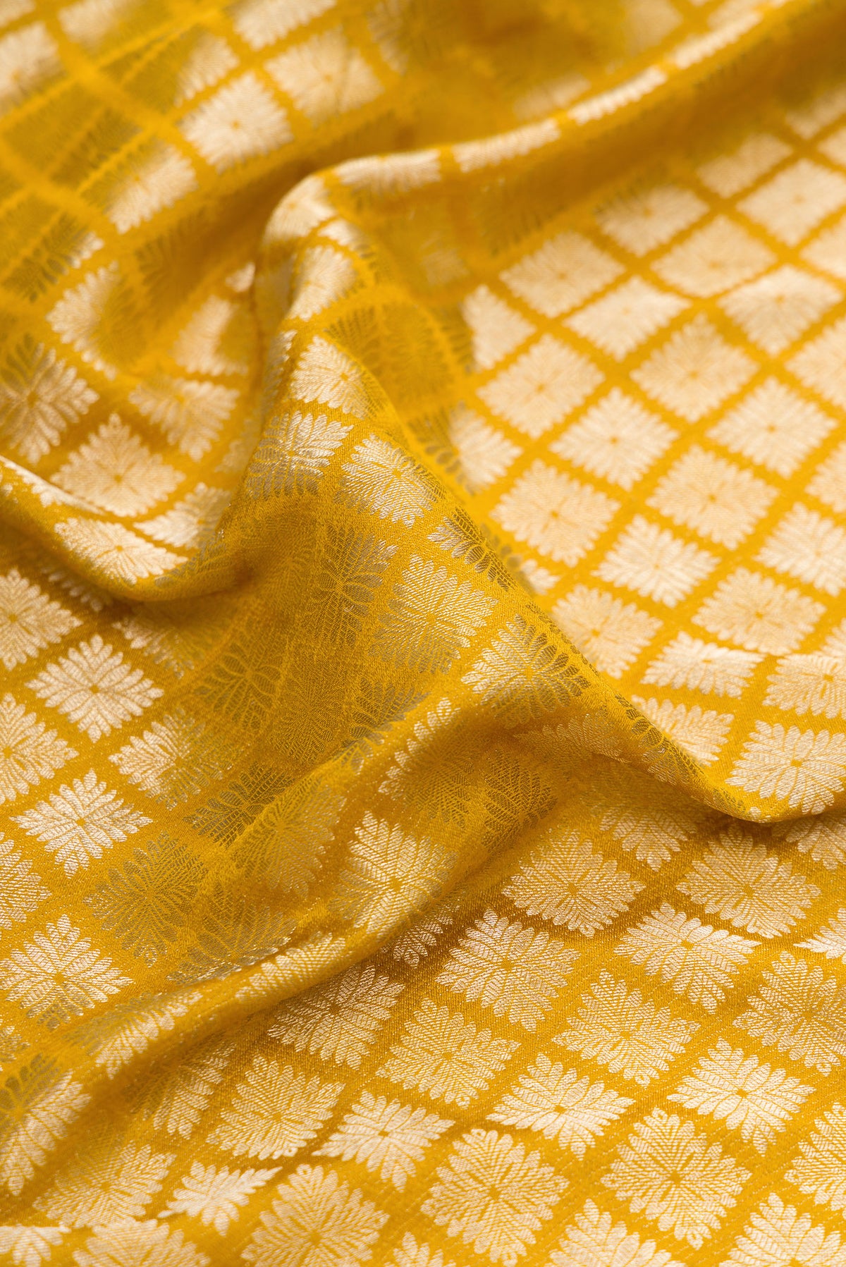 Close up of Mustard Dual Tone Mysore Crepe Saree with Zari Brocade on the body and Zari Border.  displaying folds