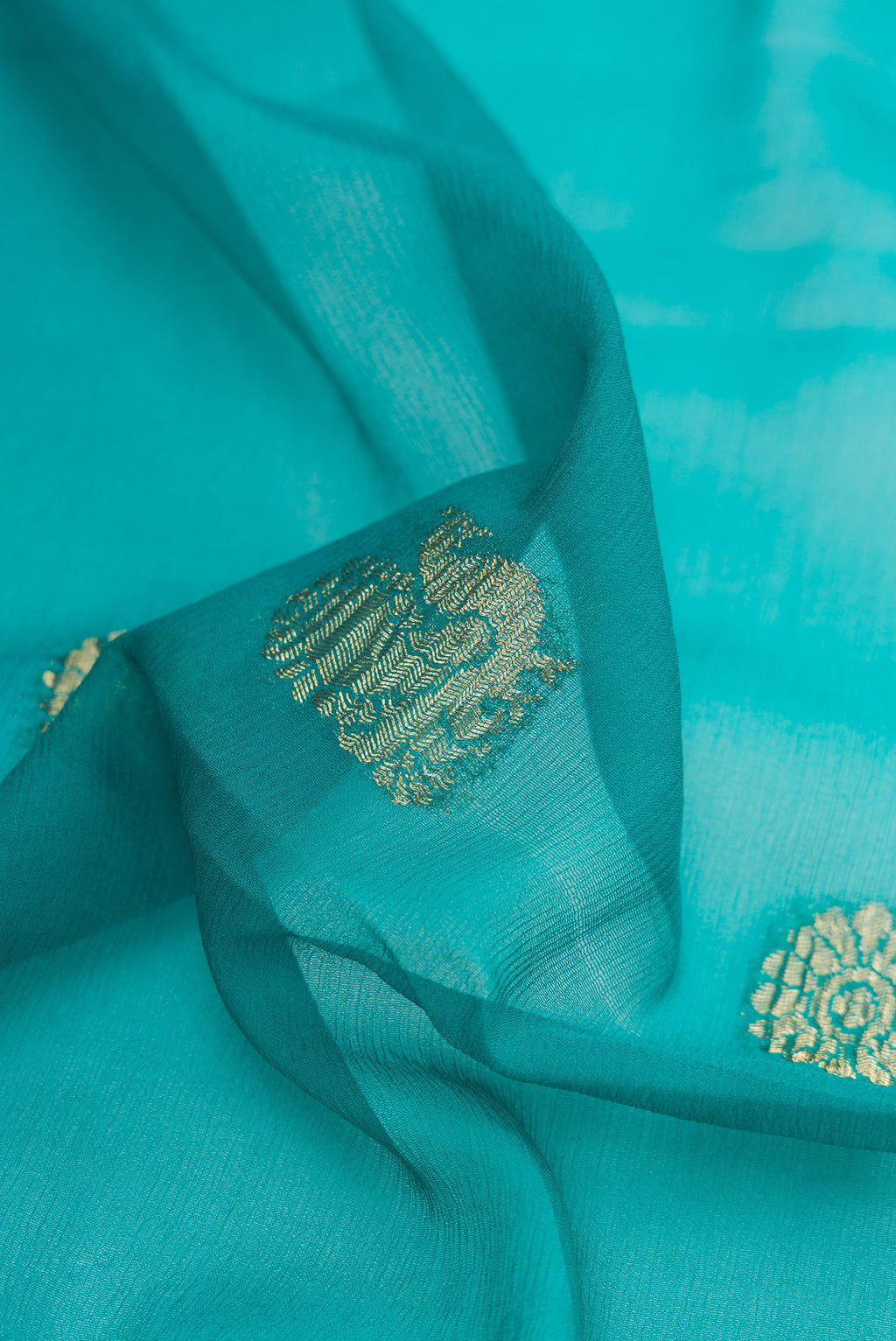 Close up of Peacock Blue Mysore Georgette Saree with Zari Butta on the body and Zari Border.  displaying folds