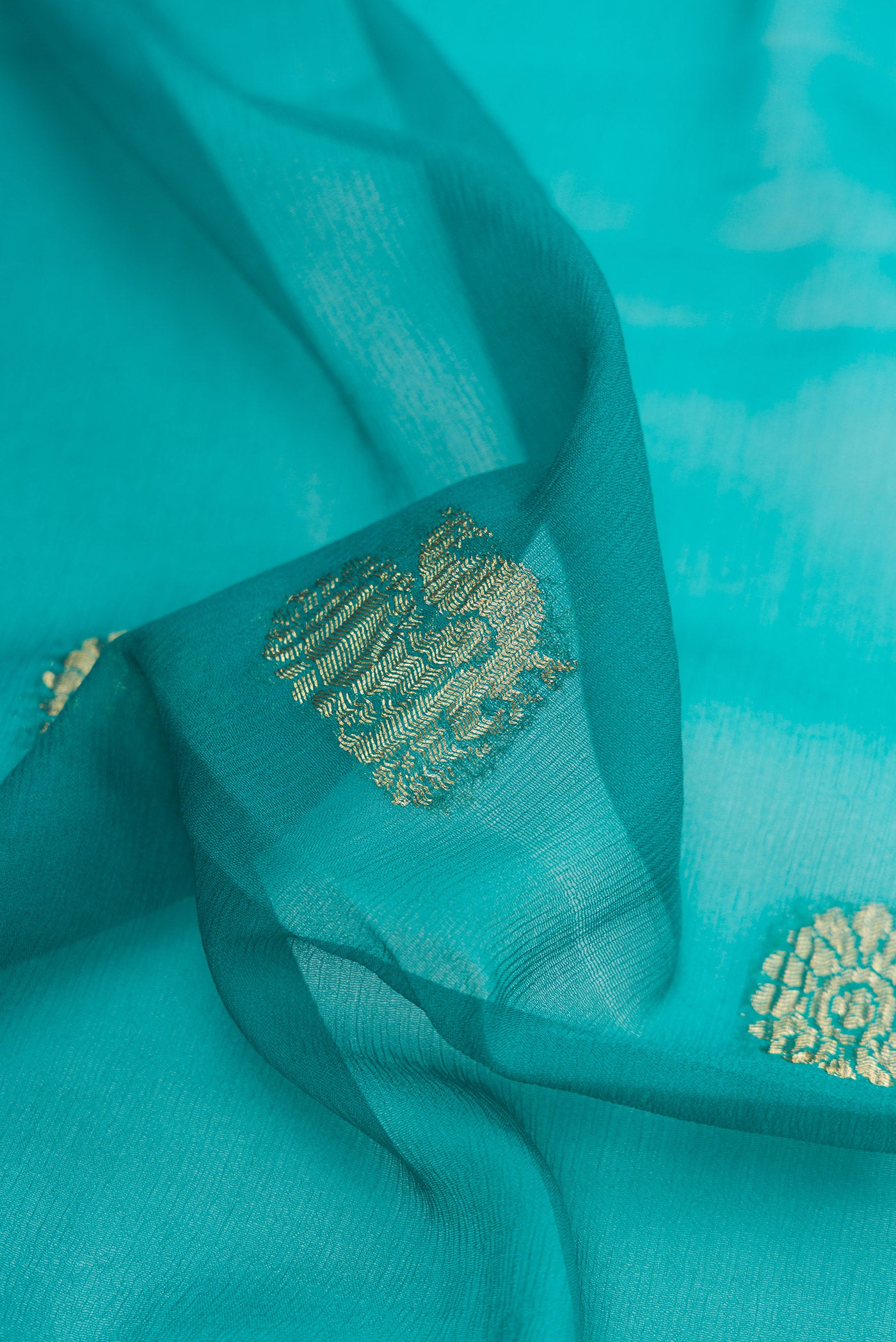 Close up of Peacock Blue Mysore Georgette Saree with Zari Butta on the body and Zari Border.  displaying folds