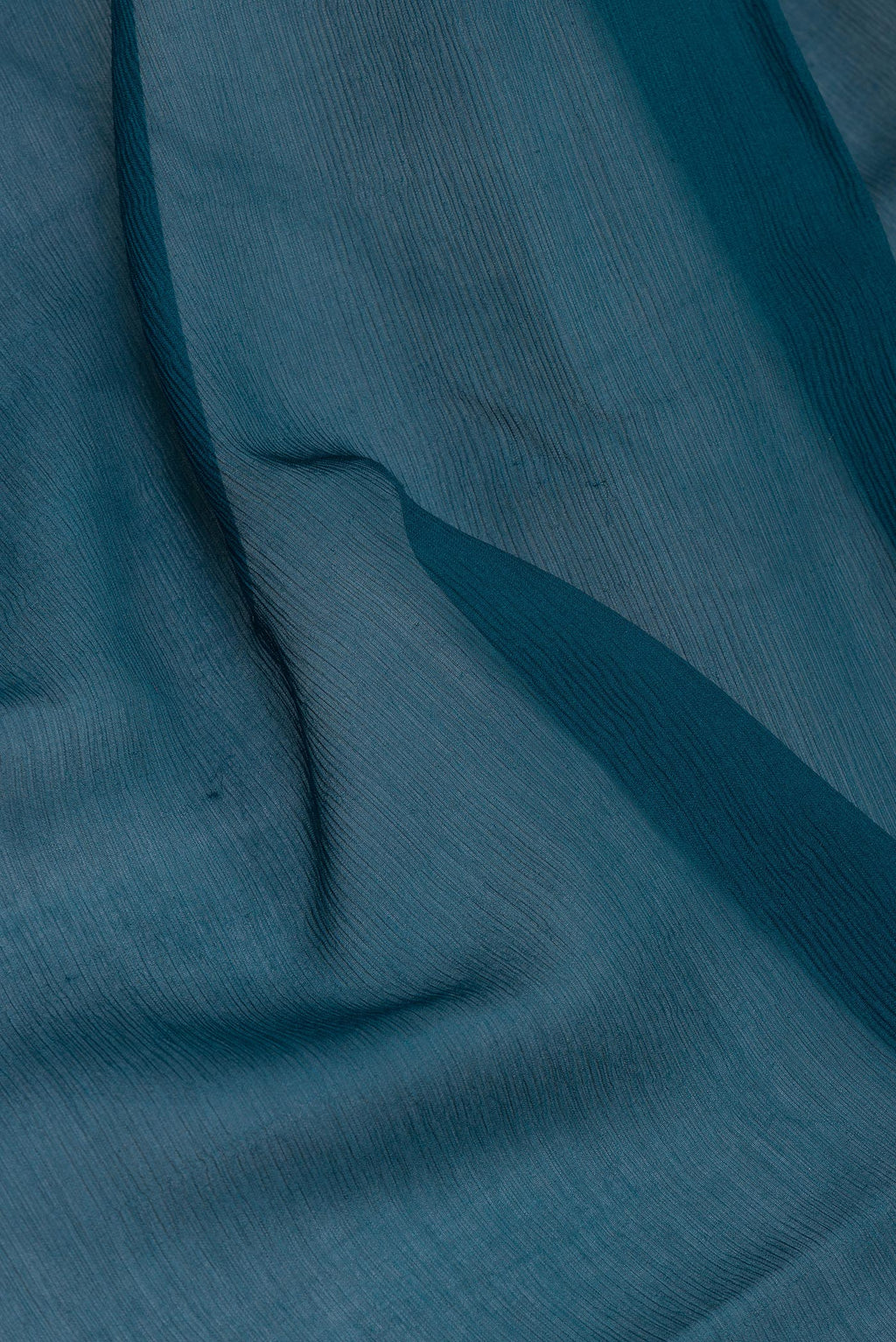 Close up of Peacock Blue Mysore Chiffon Saree with Plain Body and Zari Border.  displaying folds