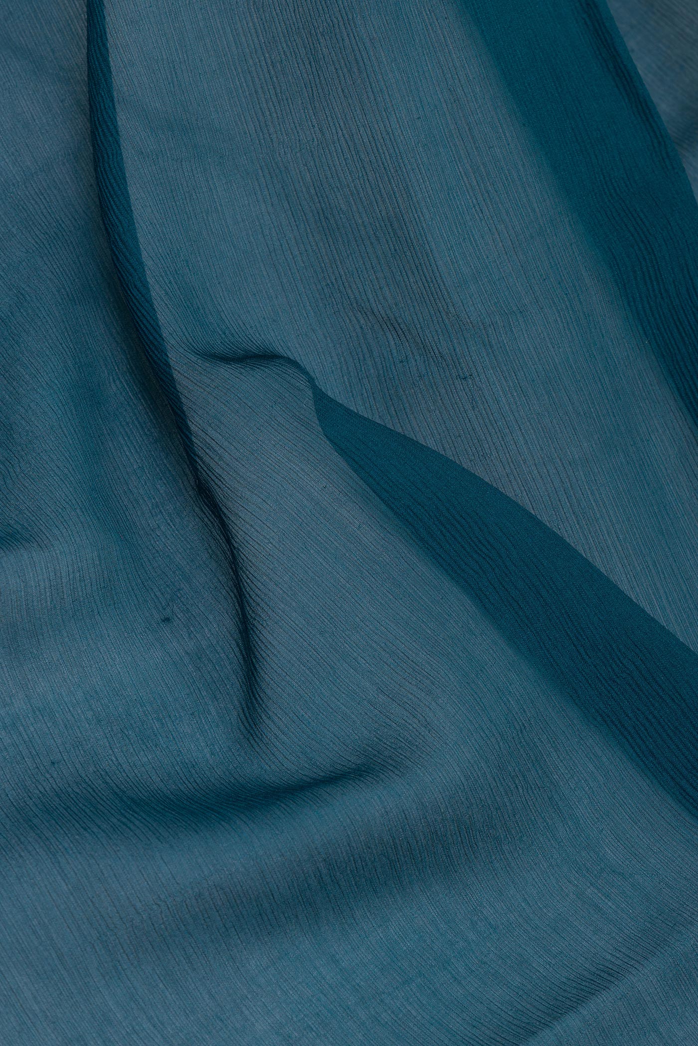Close up of Peacock Blue Mysore Chiffon Saree with Plain Body and Zari Border.  displaying folds