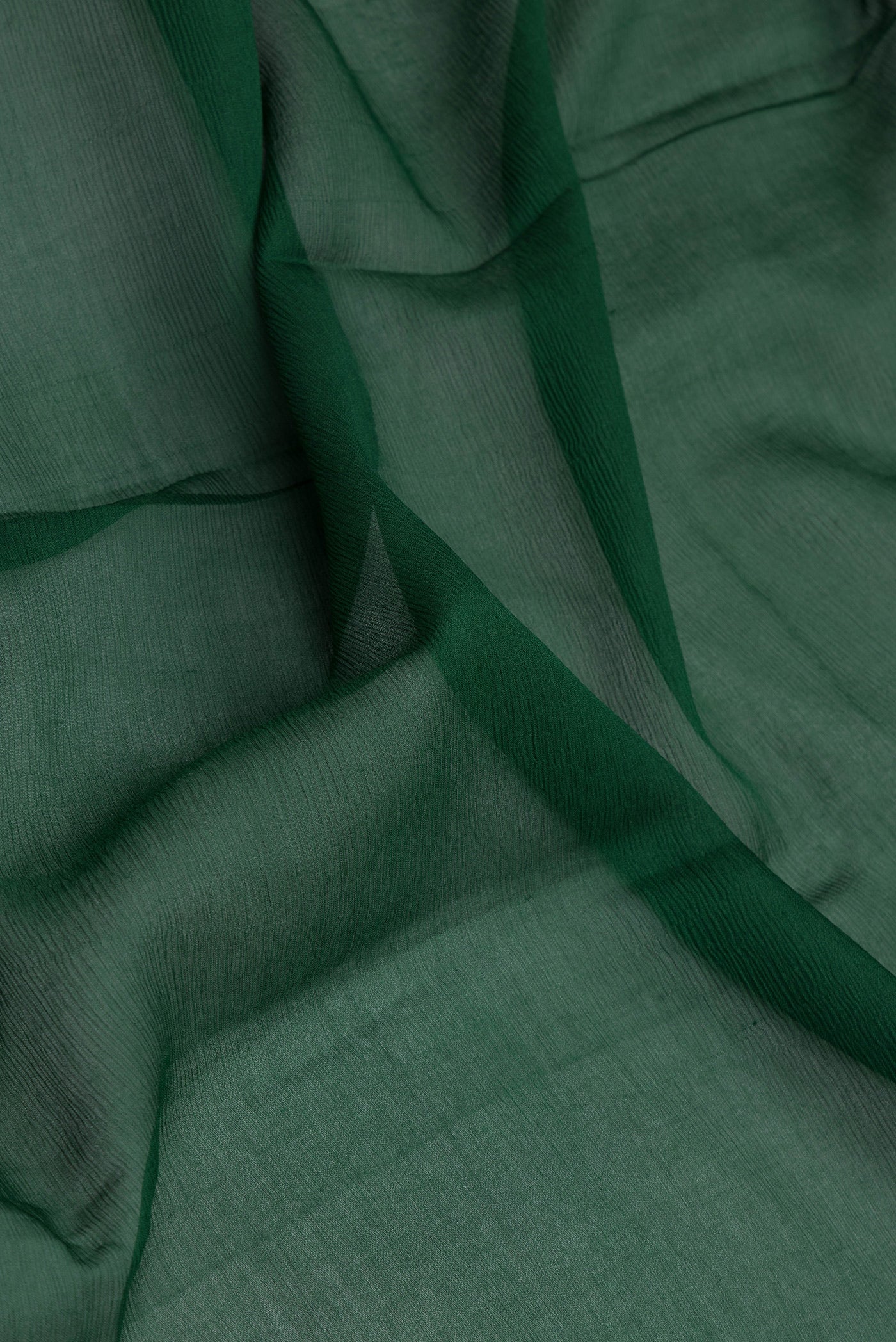 Close up of Bottle Green Mysore Chiffon Saree with Plain Body and Zari Border.  displaying folds