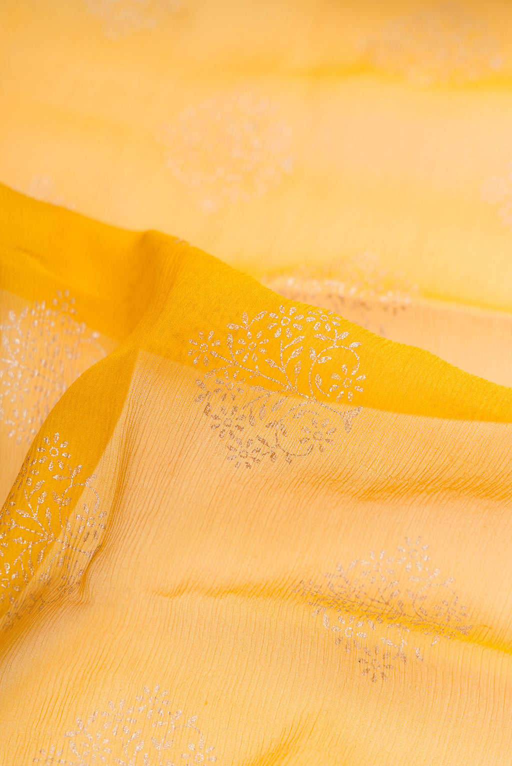 Close up of Yellow Dual Tone Mysore Chiffon Saree with Printed design on the body and Zari Border.  displaying folds