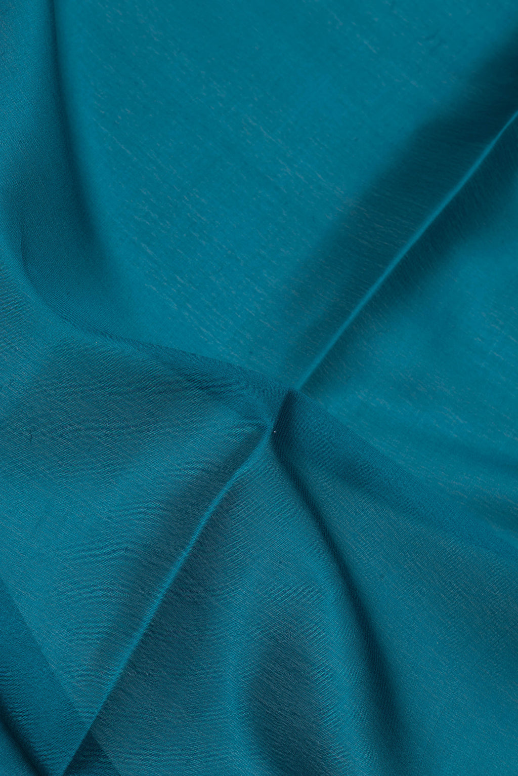 Close up of Peacock Blue Mysore Silk Saree with Plain Body and Zari Border.  displaying folds