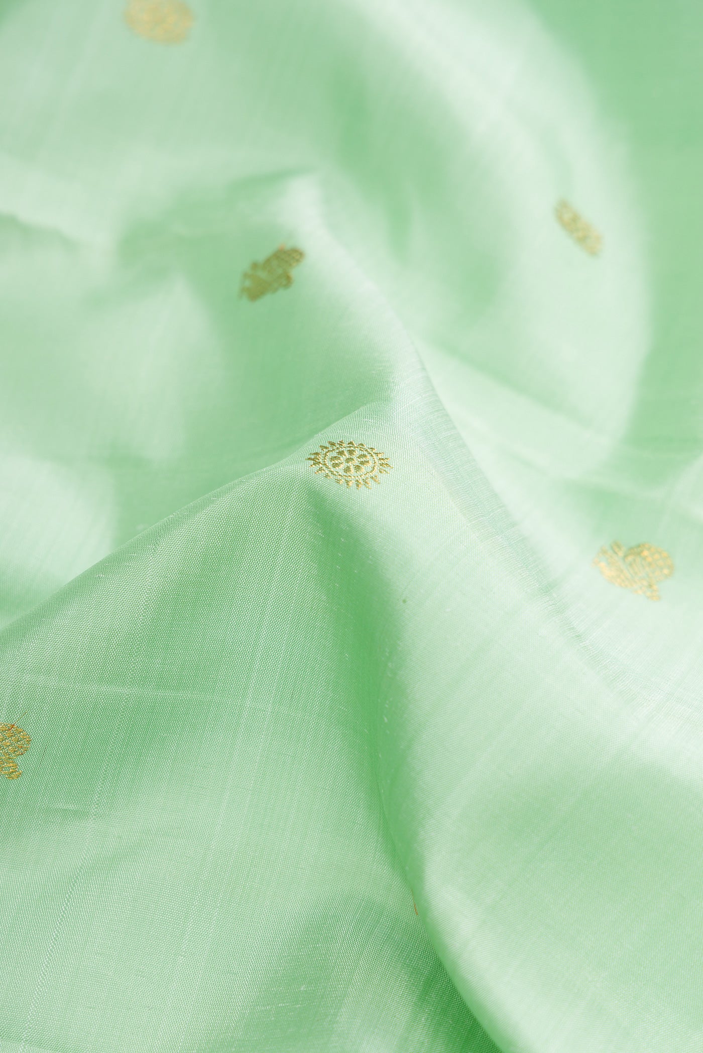 Close up of Pure Silk Pure Zari Light Green Dual Tone Kanjivaram Saree with Zari Butta on the body and Zari Border.  displaying folds