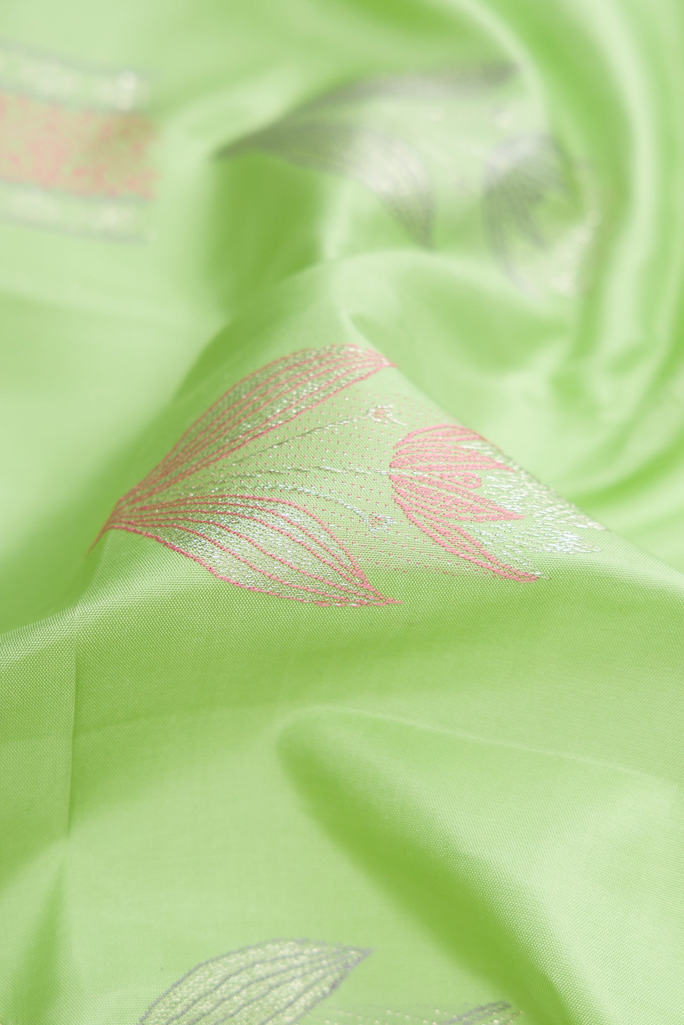 Close up of Pista Green Dual Tone Kanjivaram Silk Saree with Zari And Thread Butta on the body and Without Border.  displaying folds