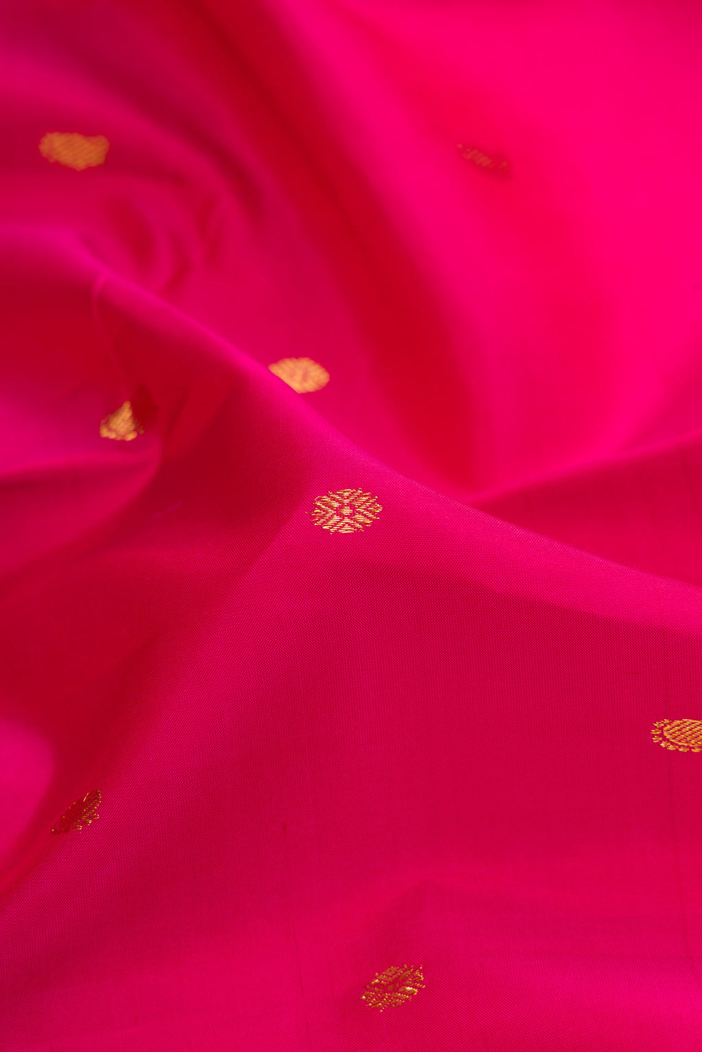 Close up of Dark Pink Dual Tone Kanjivaram Silk Saree with Zari Butta on the body and Zari Border.  displaying folds