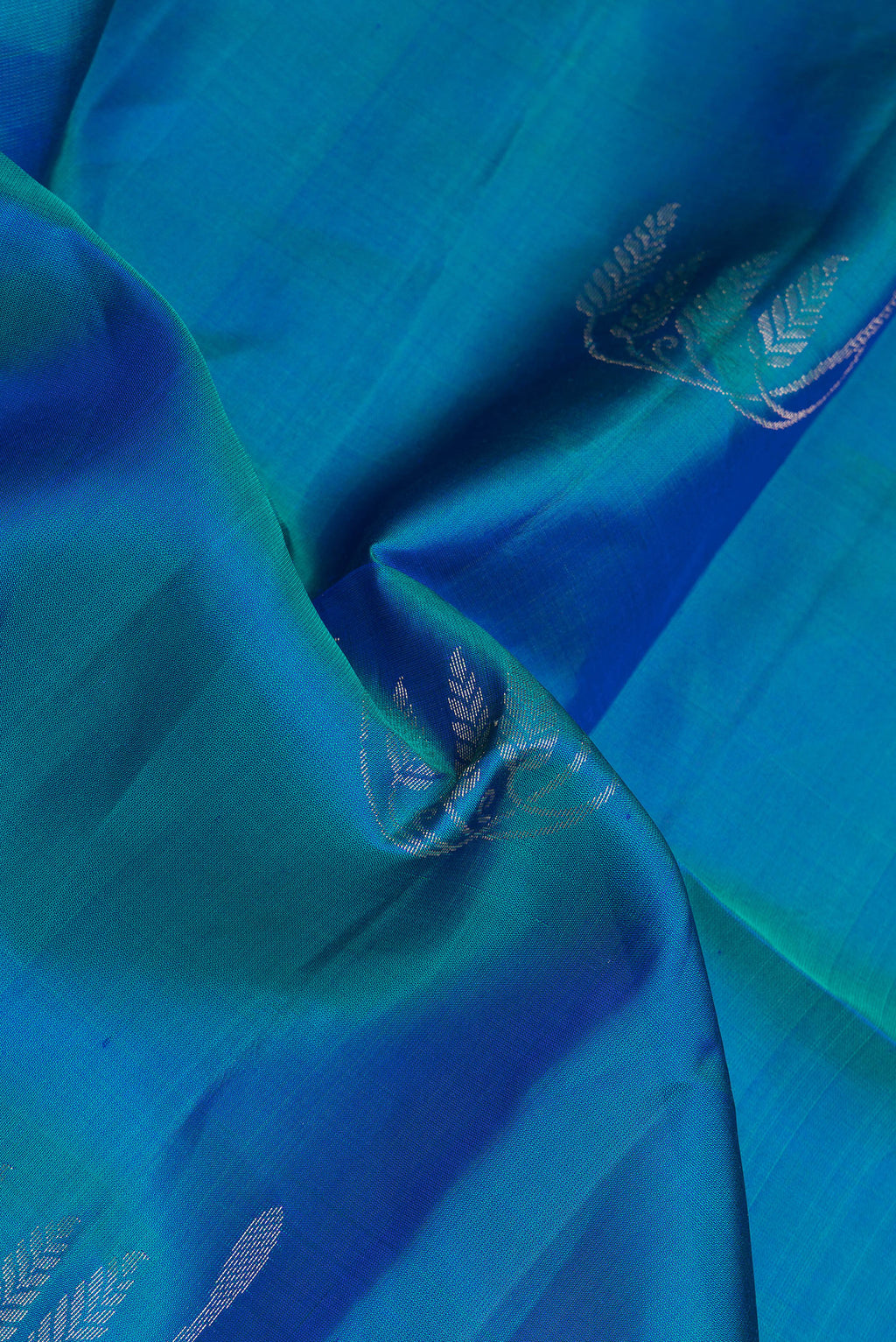 Close up of Peacock Blue Dual Tone Soft Silk Saree with Zari Butta on the body and Zari Border.  displaying folds