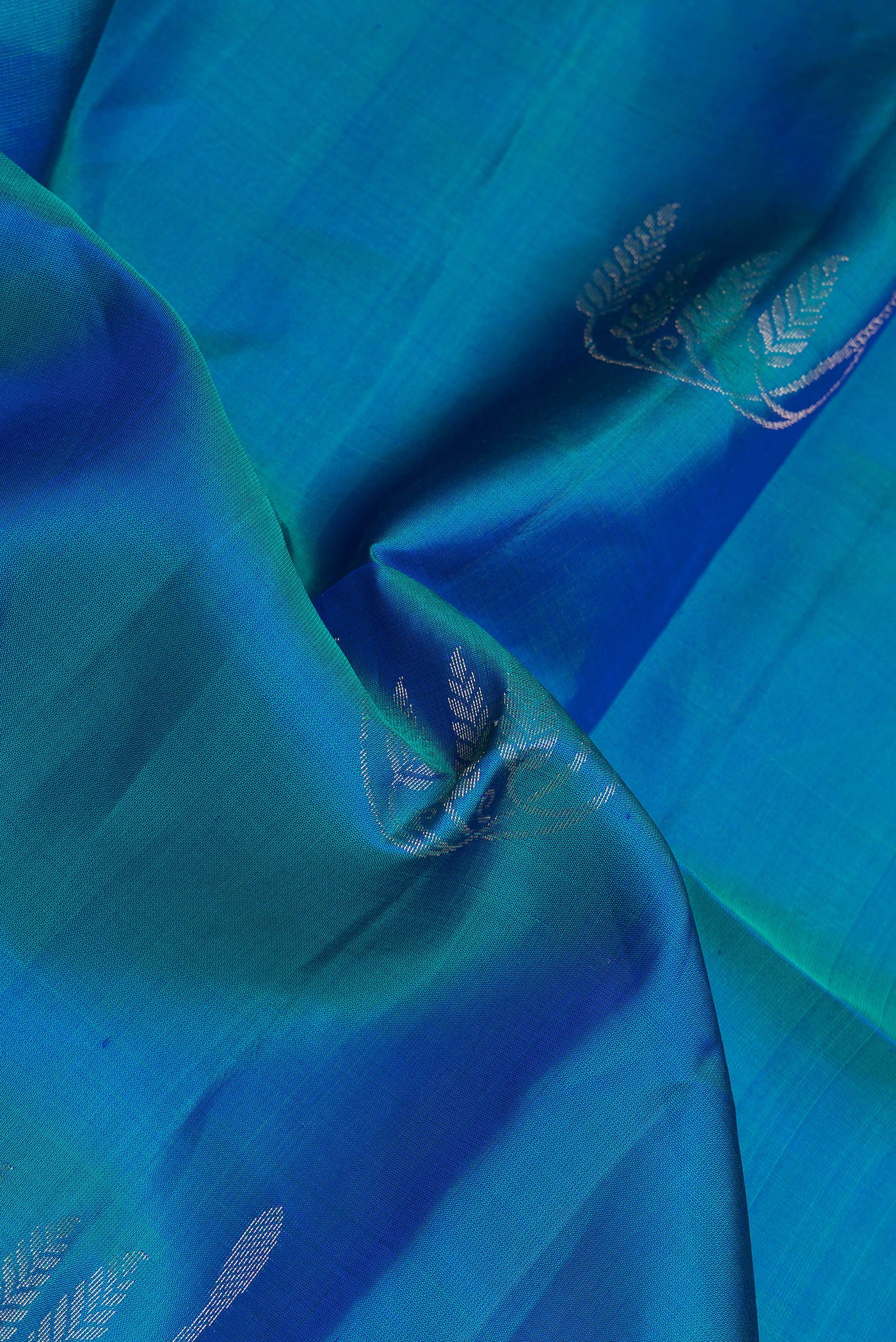 Close up of Peacock Blue Dual Tone Soft Silk Saree with Zari Butta on the body and Zari Border.  displaying folds