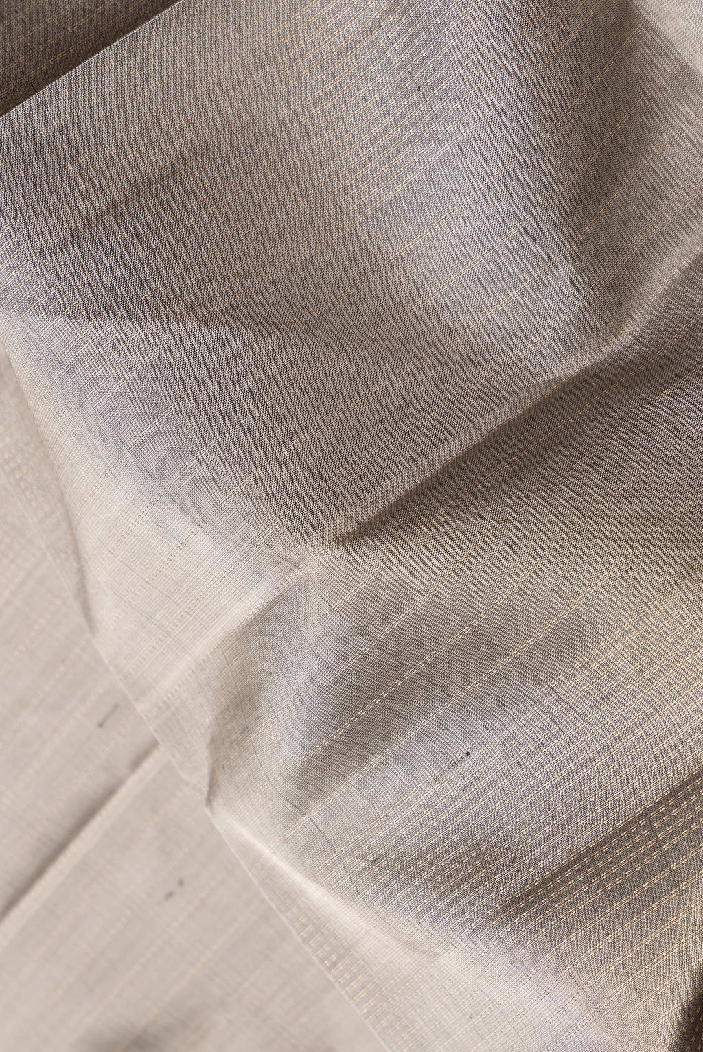 Close up of Grey Dual Tone Soft Silk Saree with Zari Butta on the body and Zari Border.  displaying folds