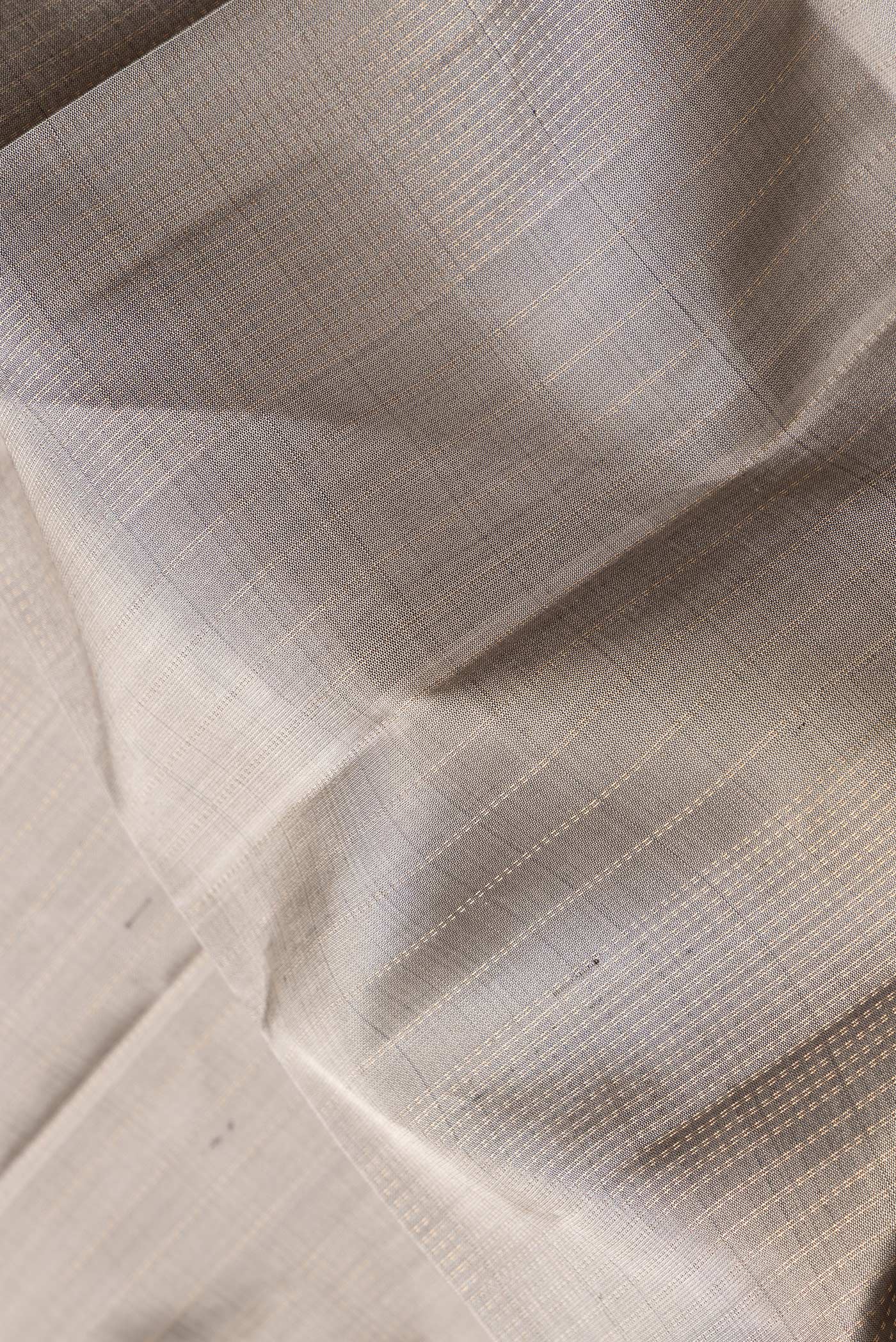 Close up of Grey Dual Tone Soft Silk Saree with Zari Butta on the body and Zari Border.  displaying folds