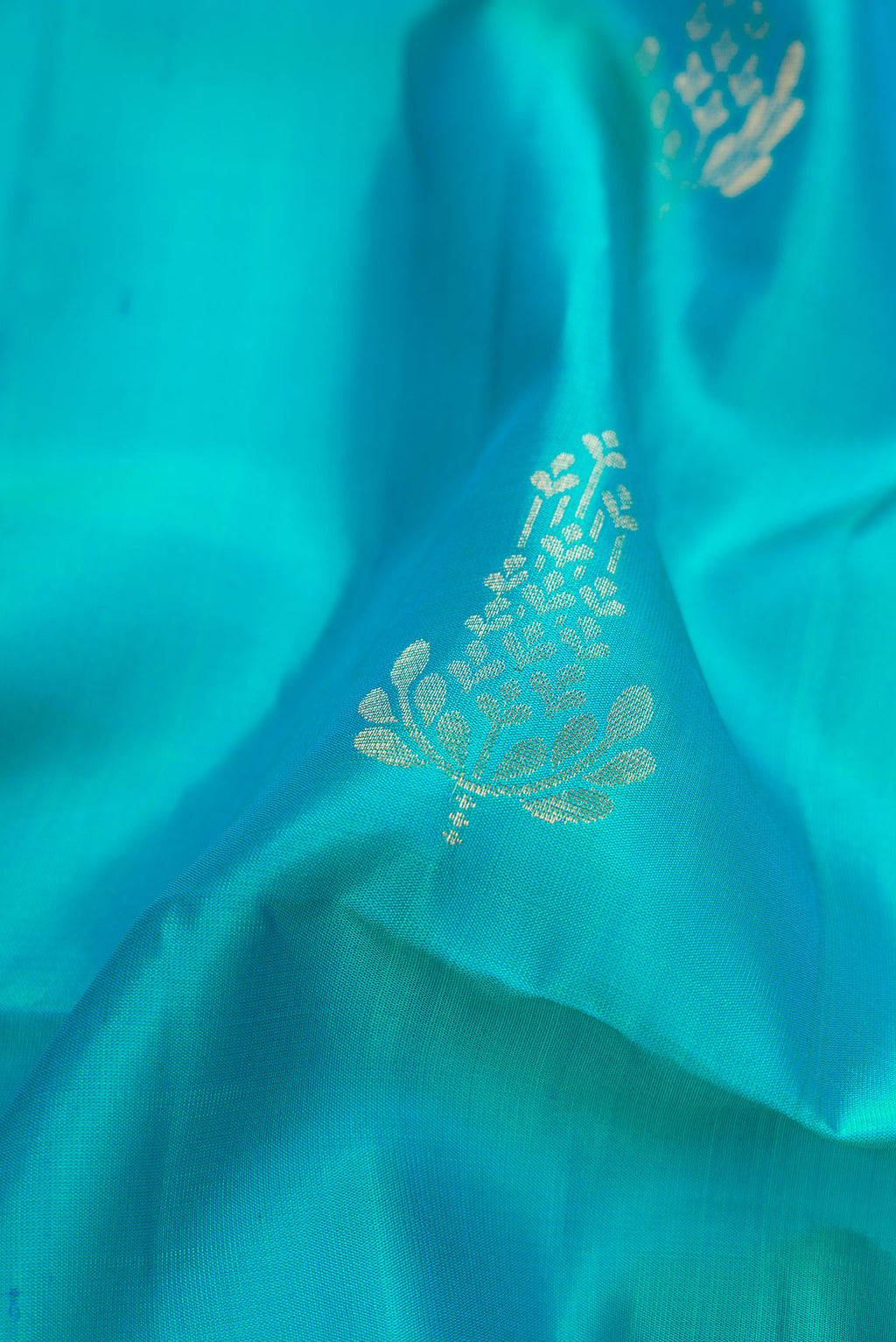 Close up of Sky Blue Dual Tone Soft Silk Saree with Zari Butta on the body and Zari Border.  displaying folds
