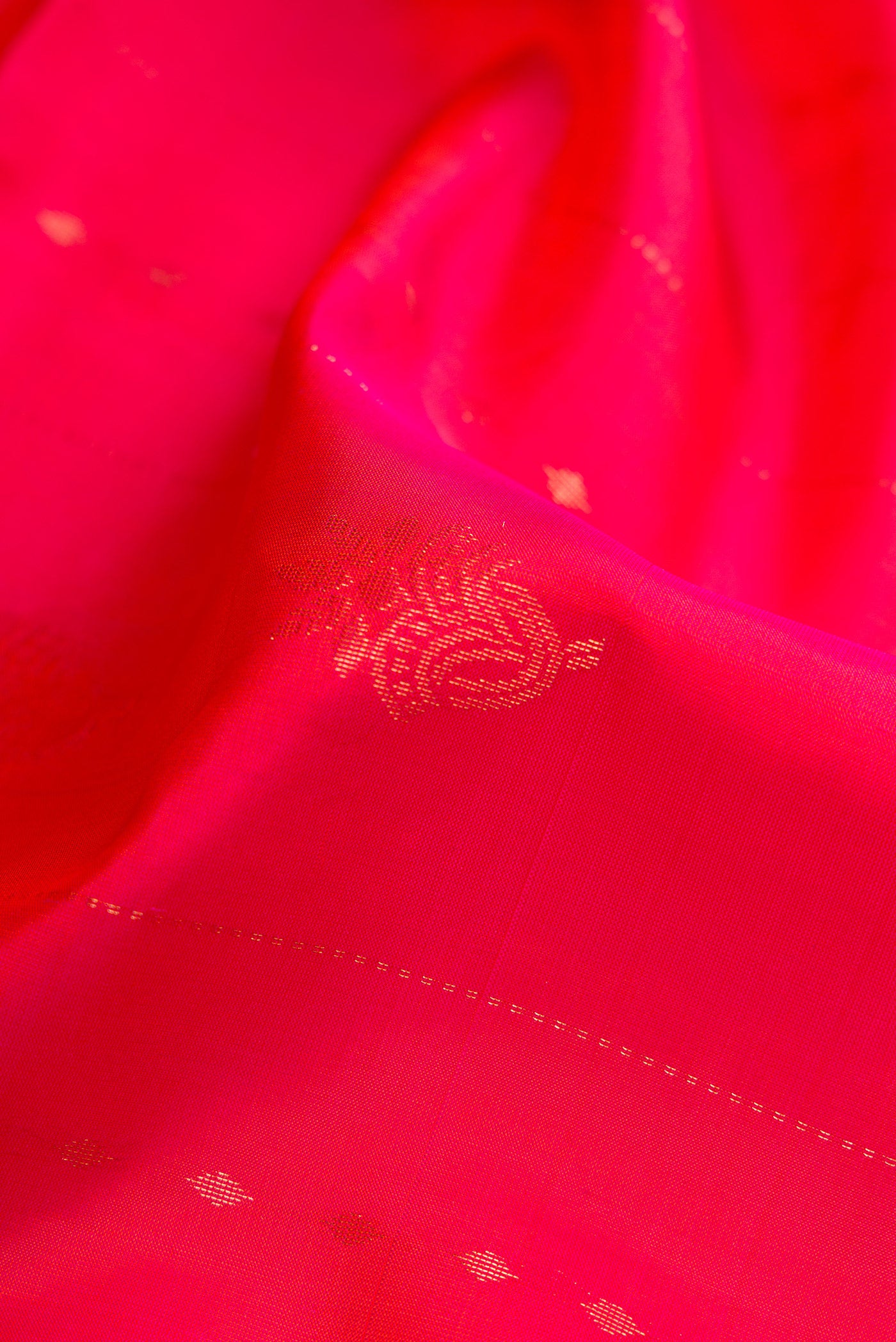 Close up of Coral Dual Tone Soft Silk Saree with Zari Butta on the body and Fancy Border.  displaying folds